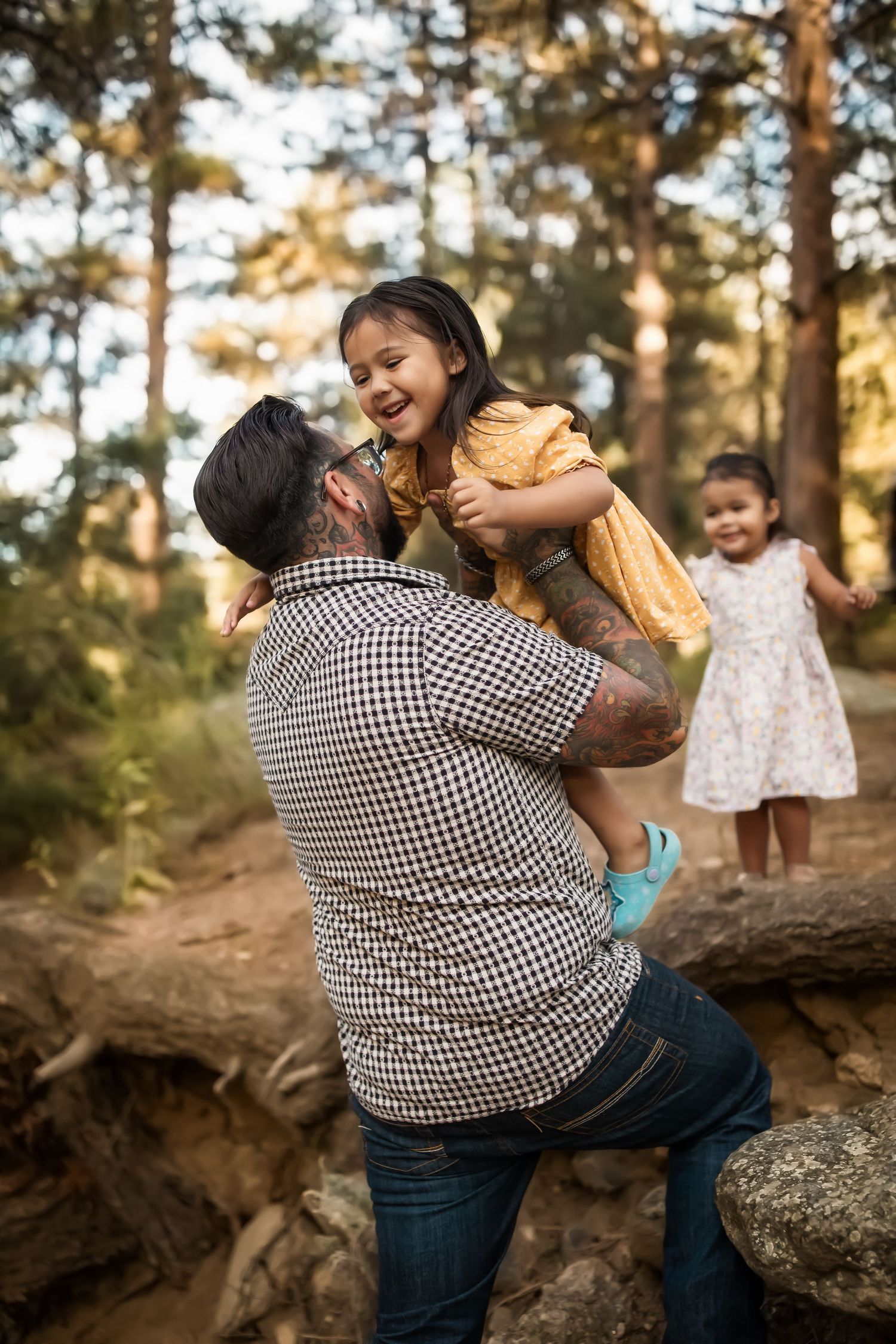 A playful moment captured in a forest setting during golden hour with people interacting joyfully near rocks.