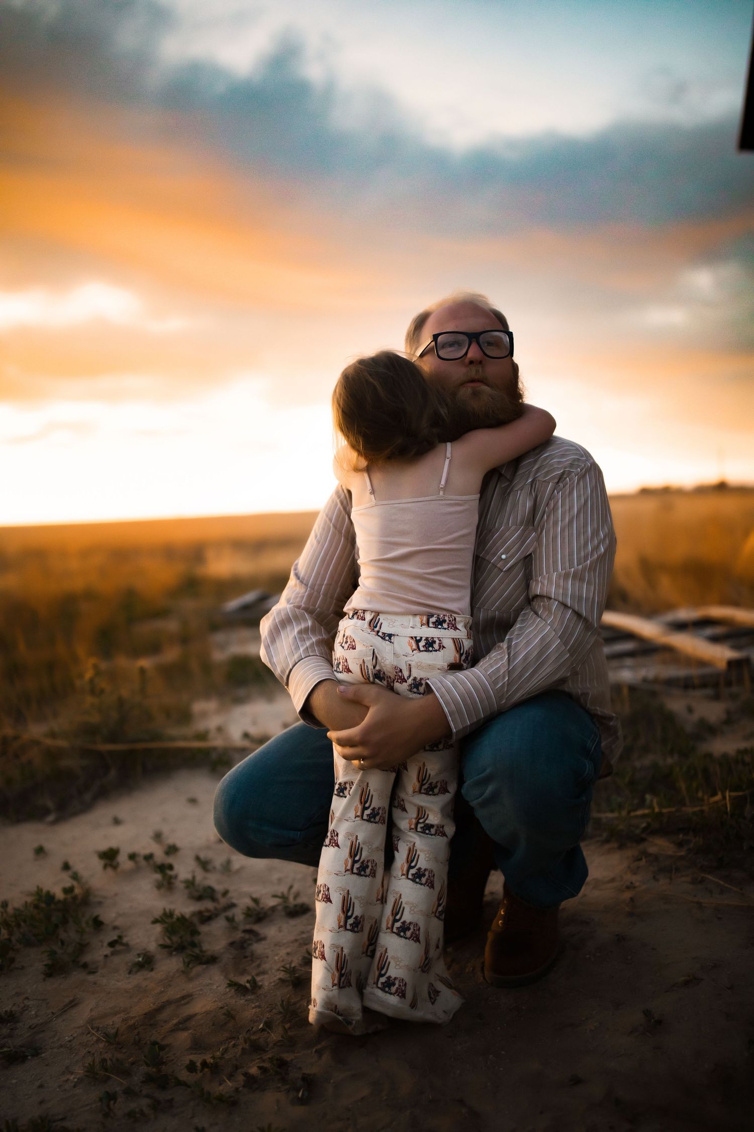 Tender moment between parent and child during sunset in an open field.