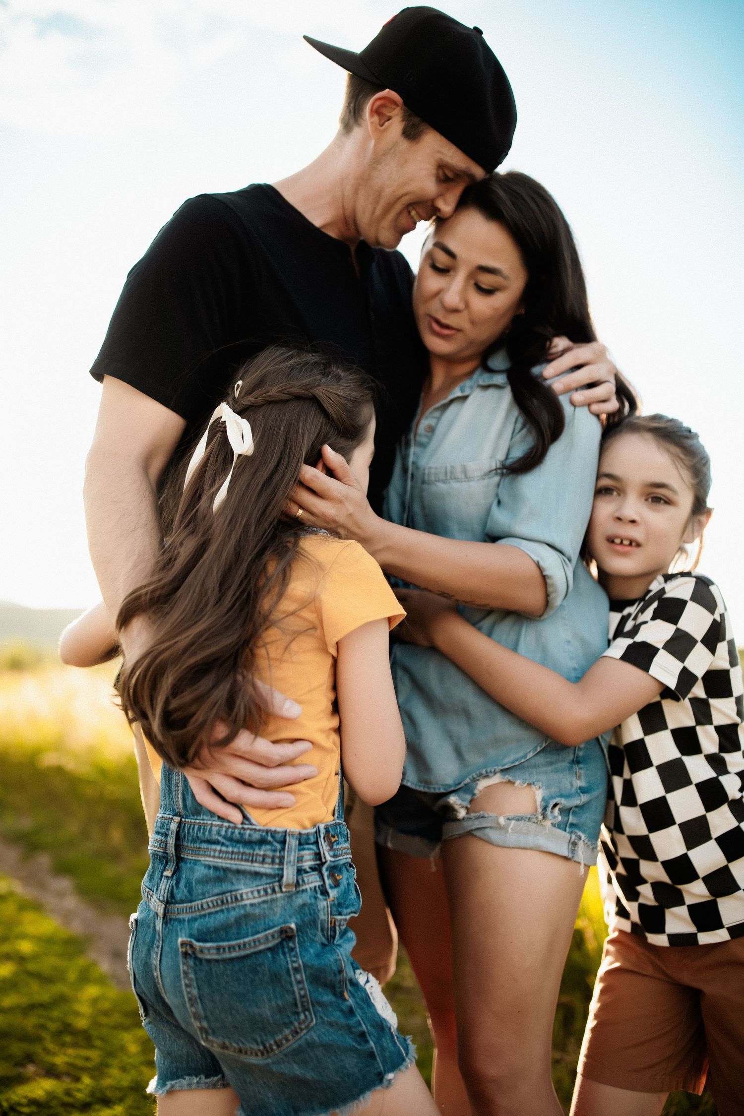 Family sharing an intimate moment together outdoors during golden hour.
