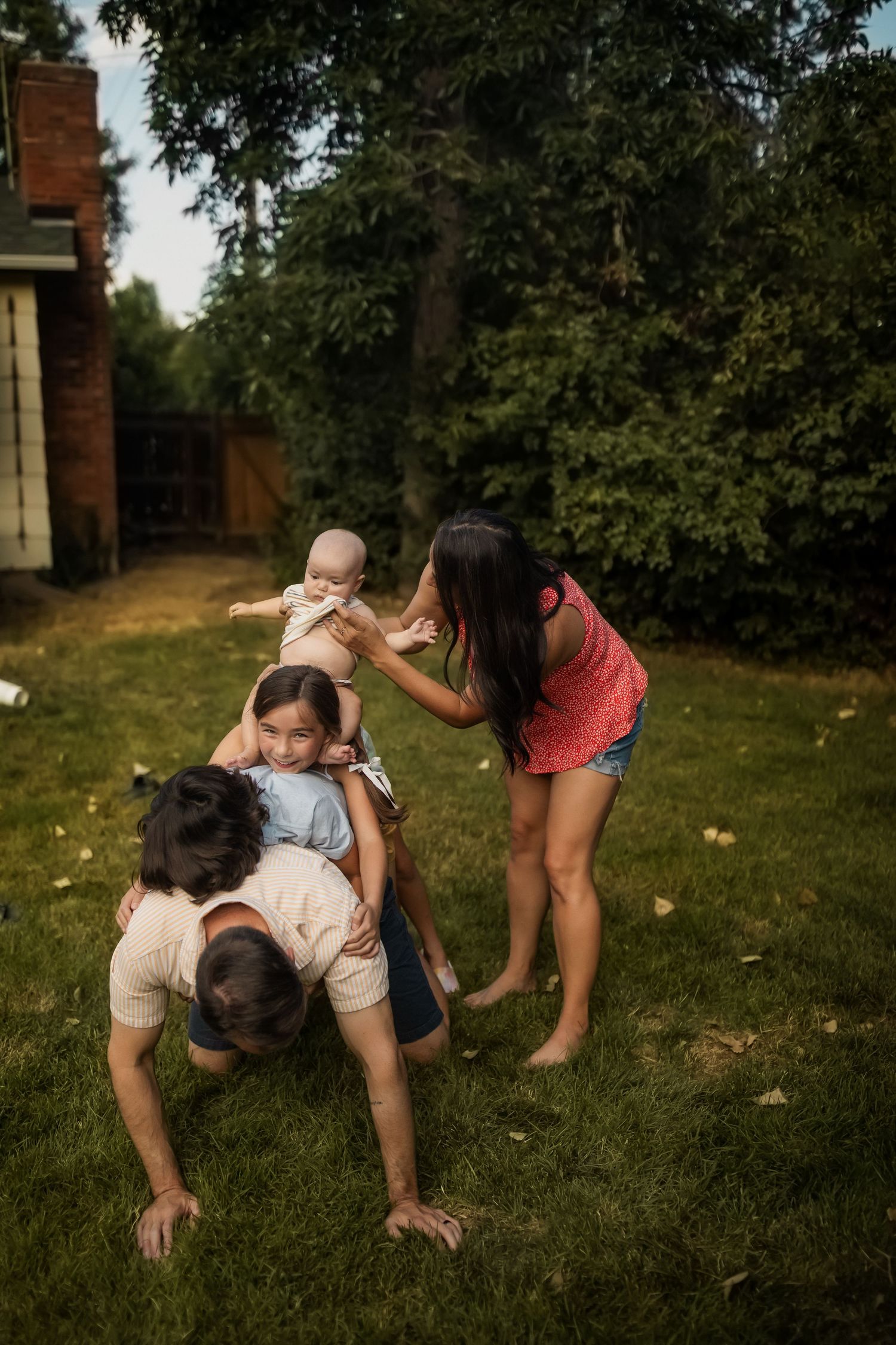 Playful outdoor scene of people crawling and interacting on green grass.