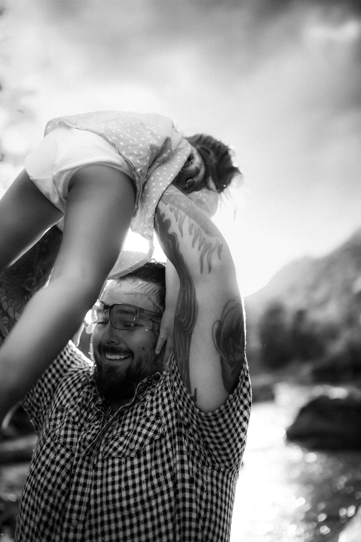 Black and white photo captures playful interaction between adult and child outdoors.