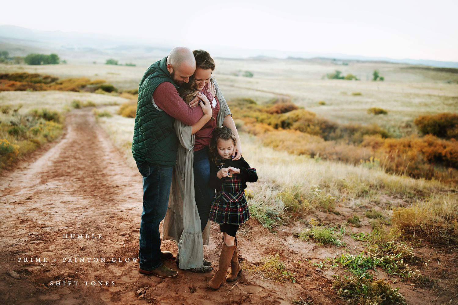 Family exploring a scenic dirt path through rolling grasslands at sunset.