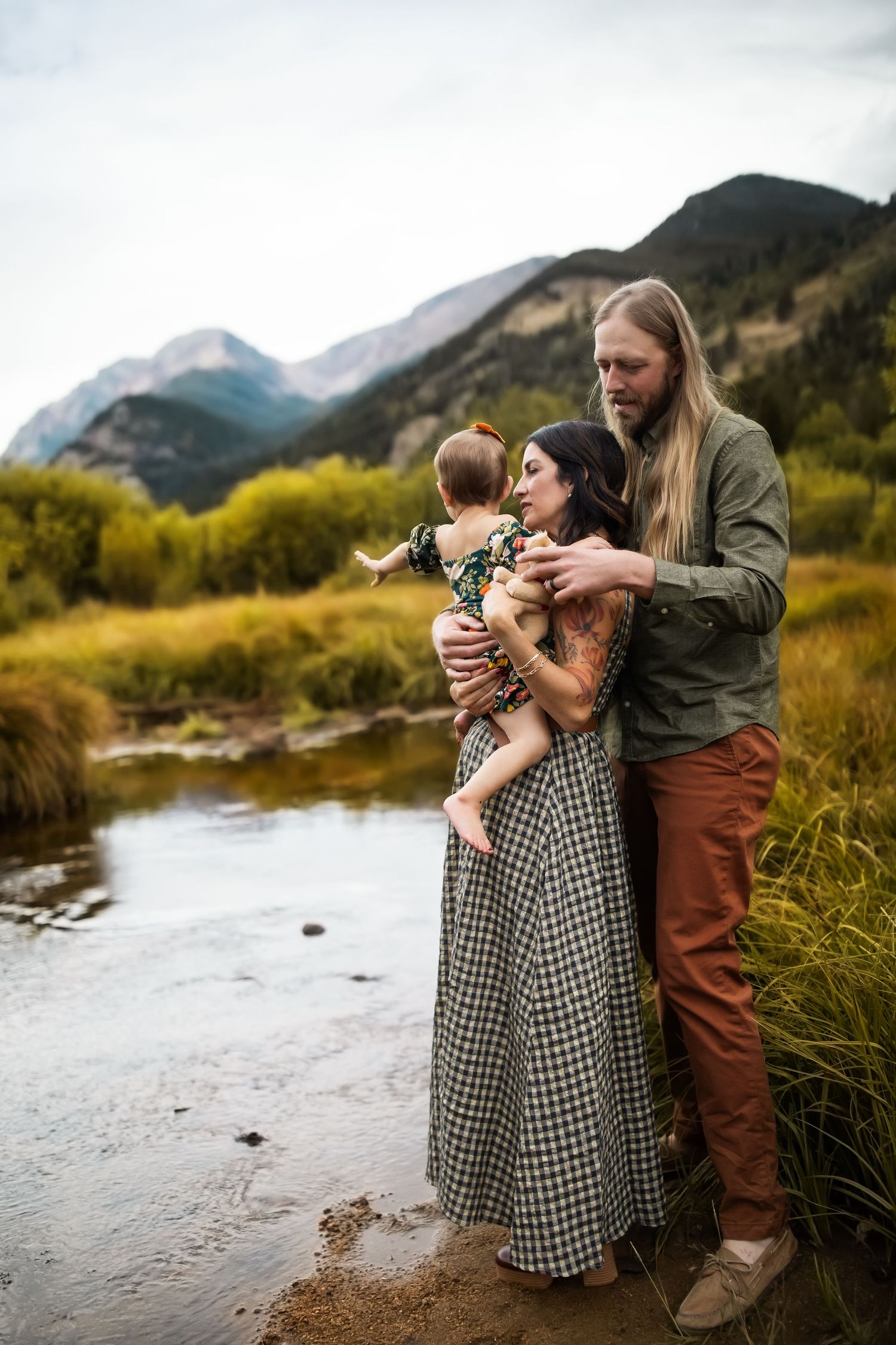 A family shares an intimate moment together by a mountain stream on an autumn afternoon in a scenic landscape.