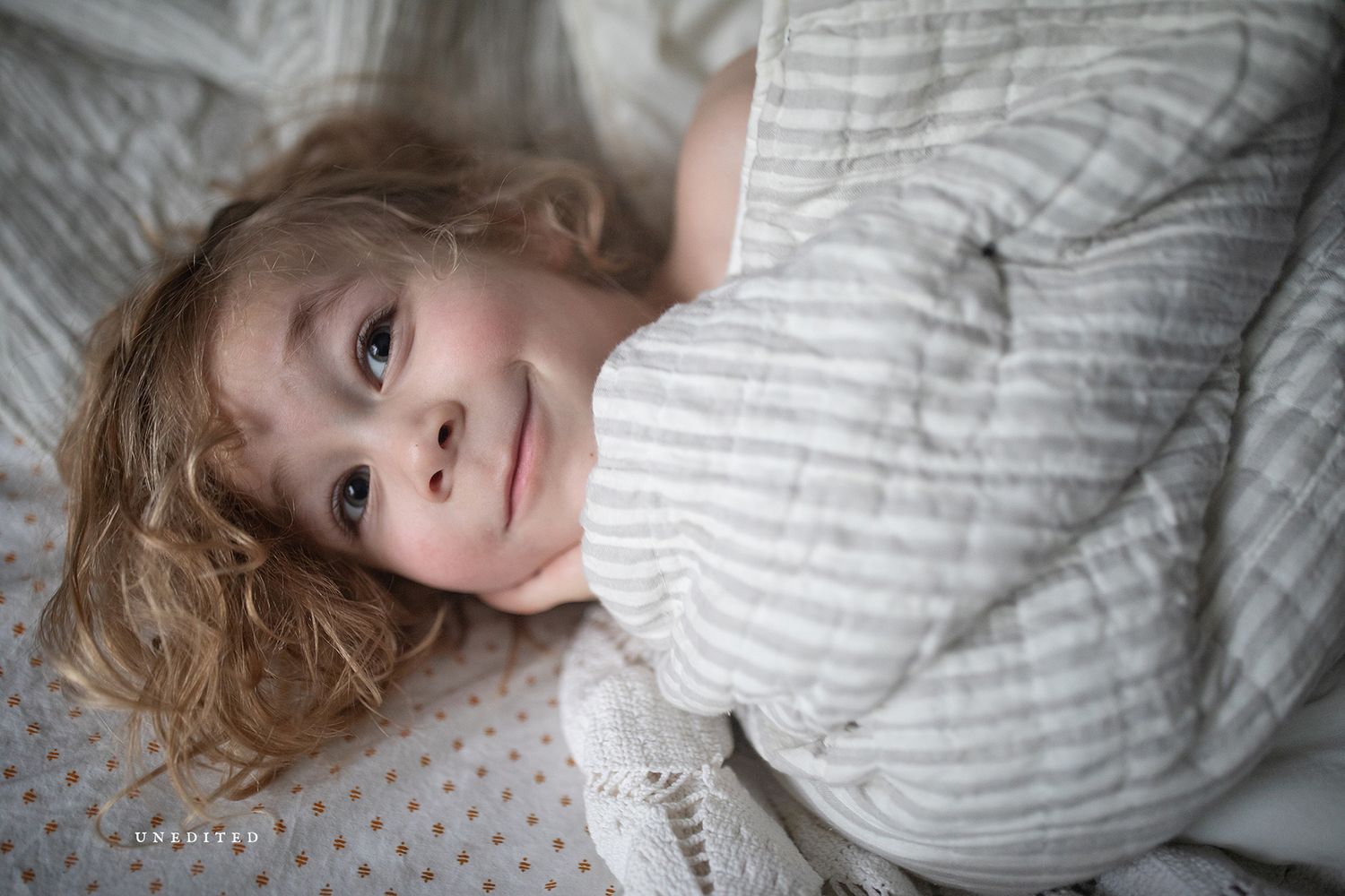 Person resting on soft gray bedding in natural window light.