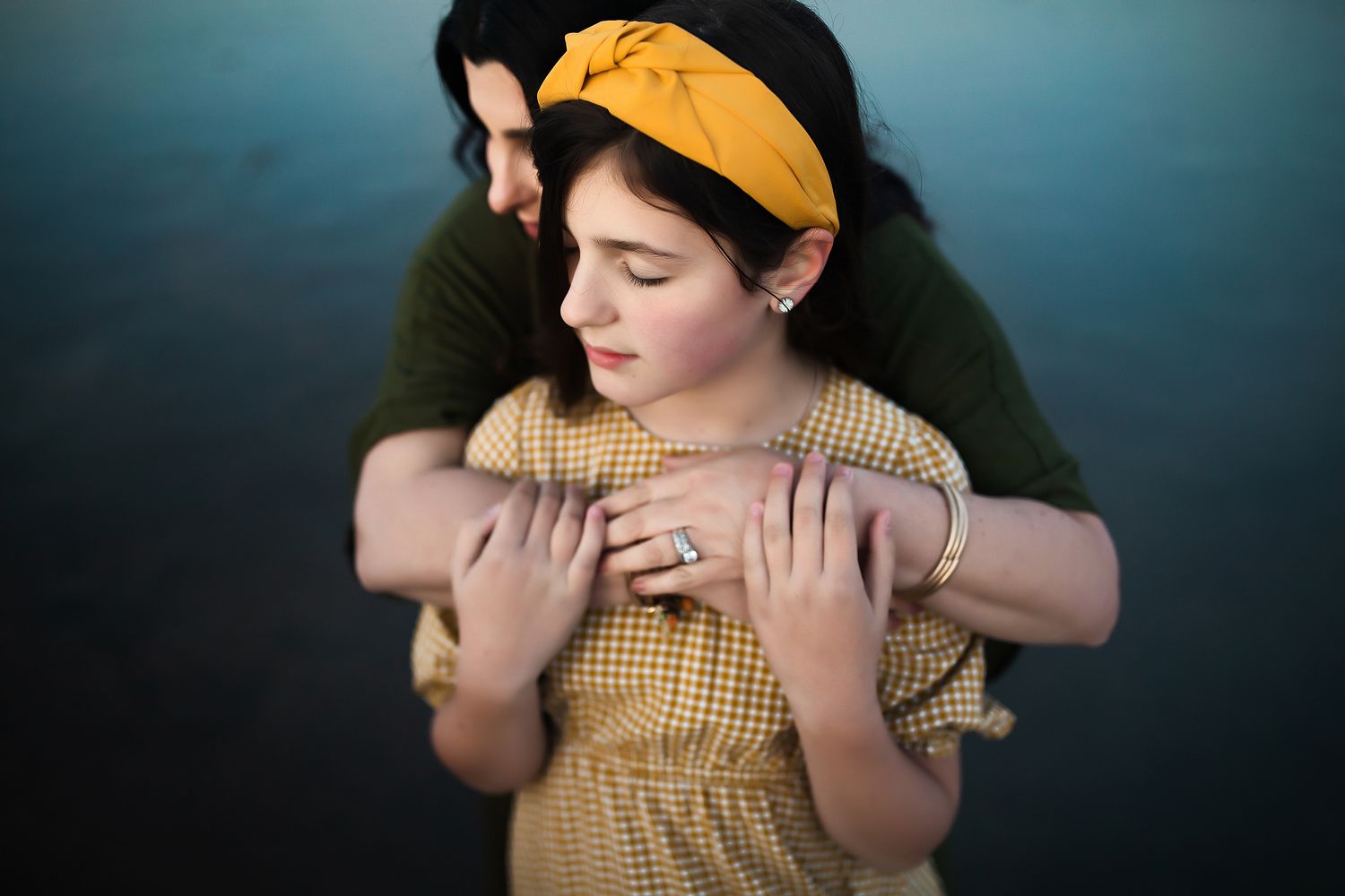 Child wearing yellow clothing against dark moody background.