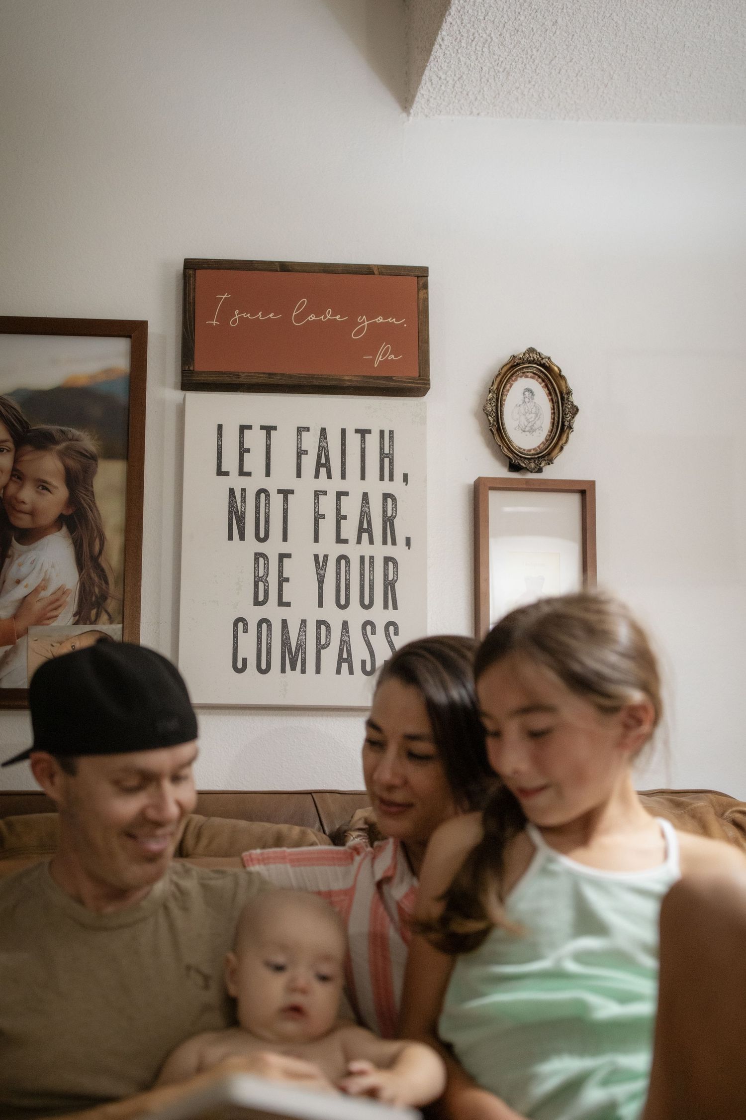 A group relaxes together on a couch with inspirational wall art reading 'Let Faith' and 'Not Fear' visible in the background.