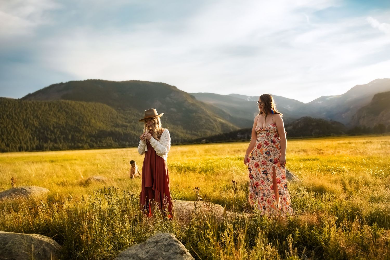 Romantic couple walking through a golden mountain meadow at sunset with sunlight streaming through the hills.