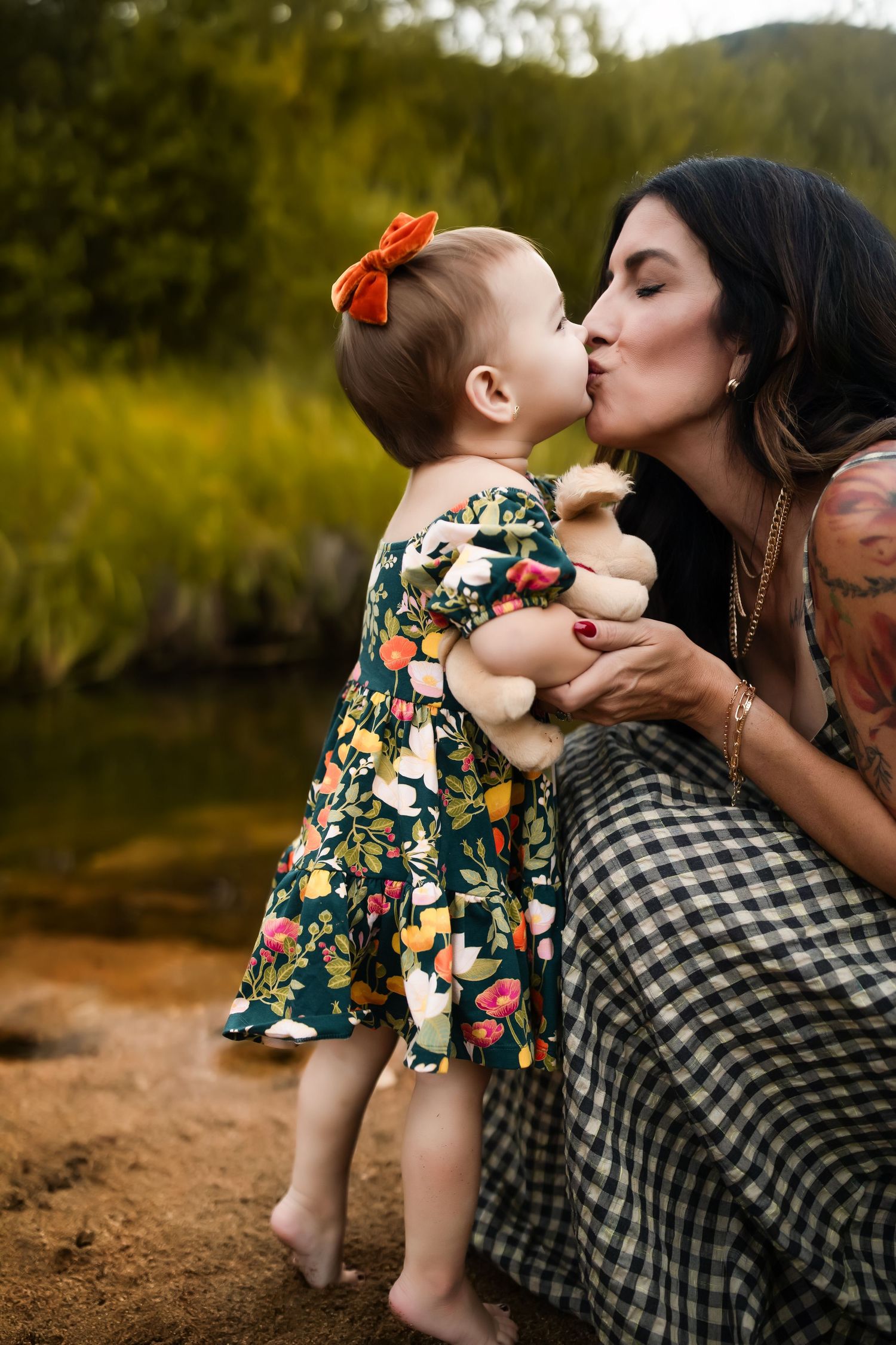 A tender moment shared between parent and child in a floral dress against a natural outdoor backdrop.