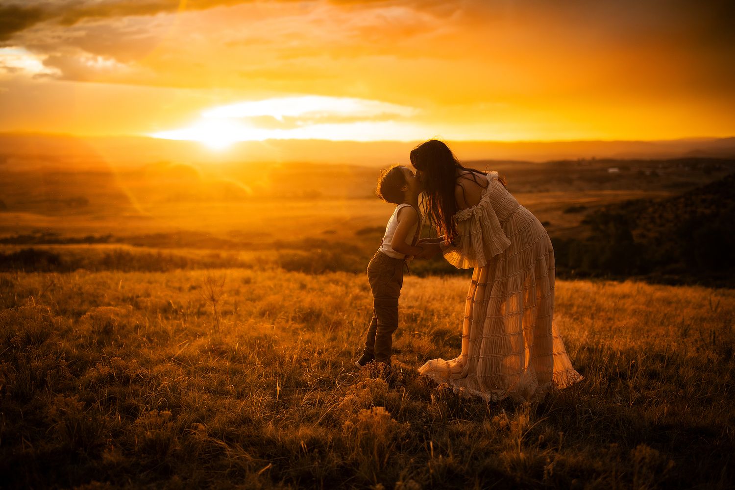 Silhouettes against a dramatic orange sunset in an open mountain landscape.