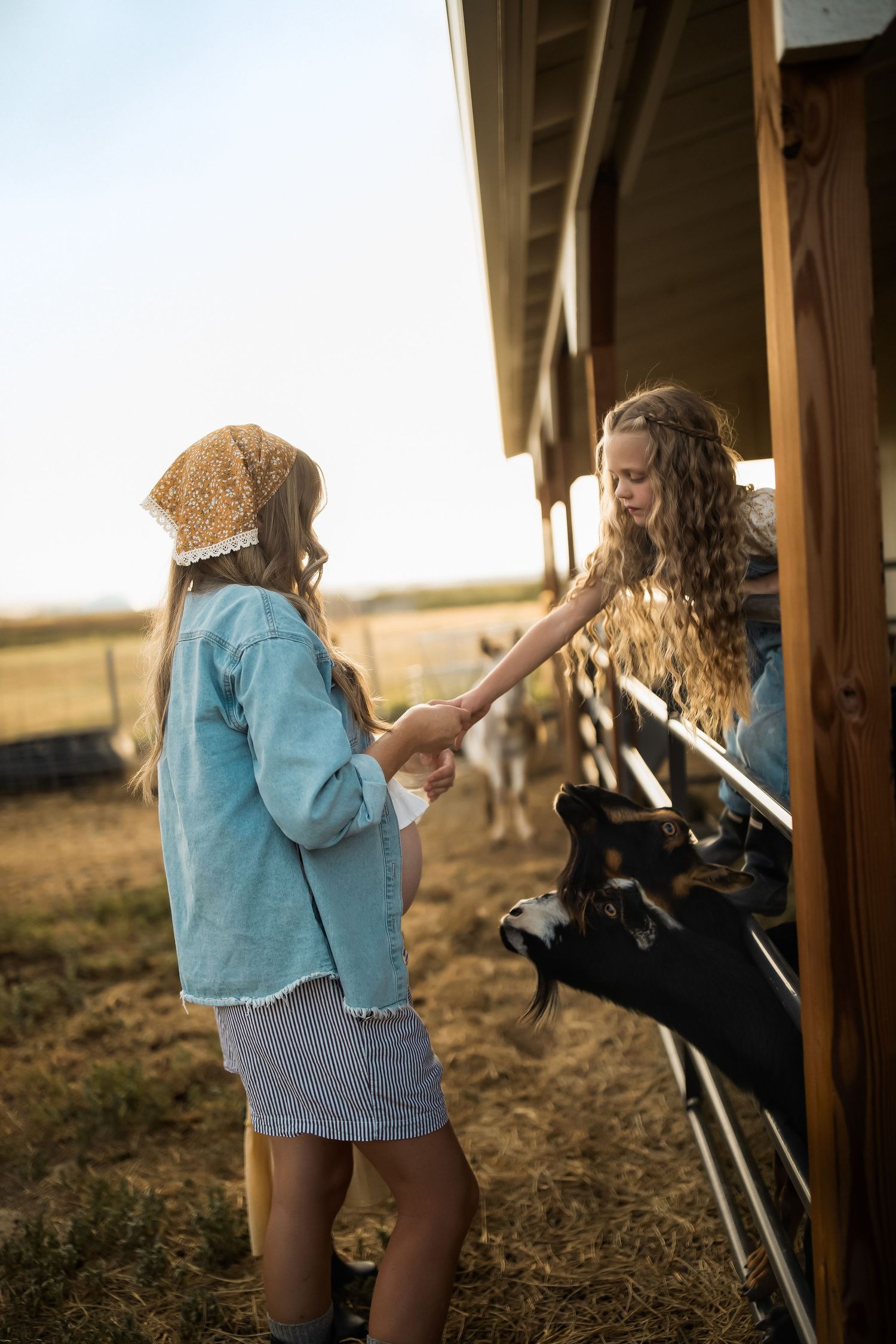 Two people sharing a playful moment near a rustic wooden barn at sunset.