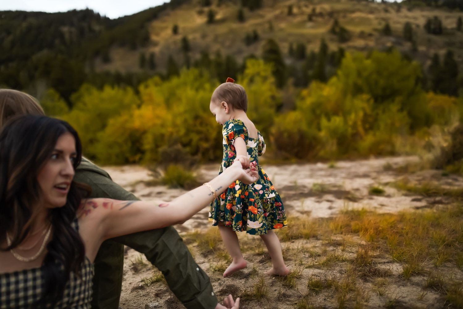 A child in a floral dress leaps joyfully across a scenic mountain landscape on an autumn afternoon.