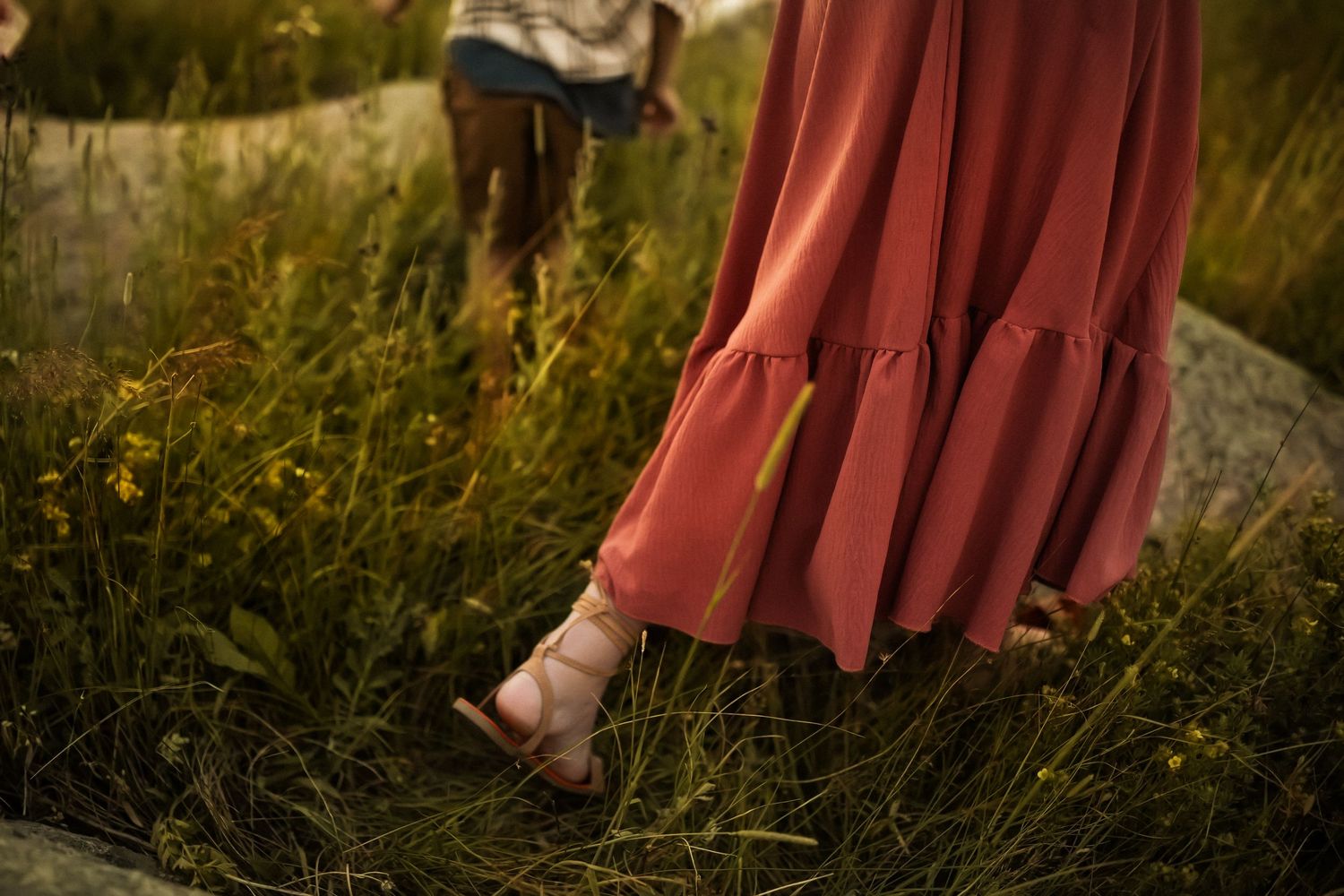 Flowing red dress swaying in a golden field at sunset with mountains in the background.