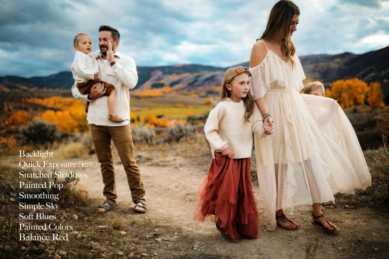 Family in white and burgundy outfits poses against autumn mountain landscape.