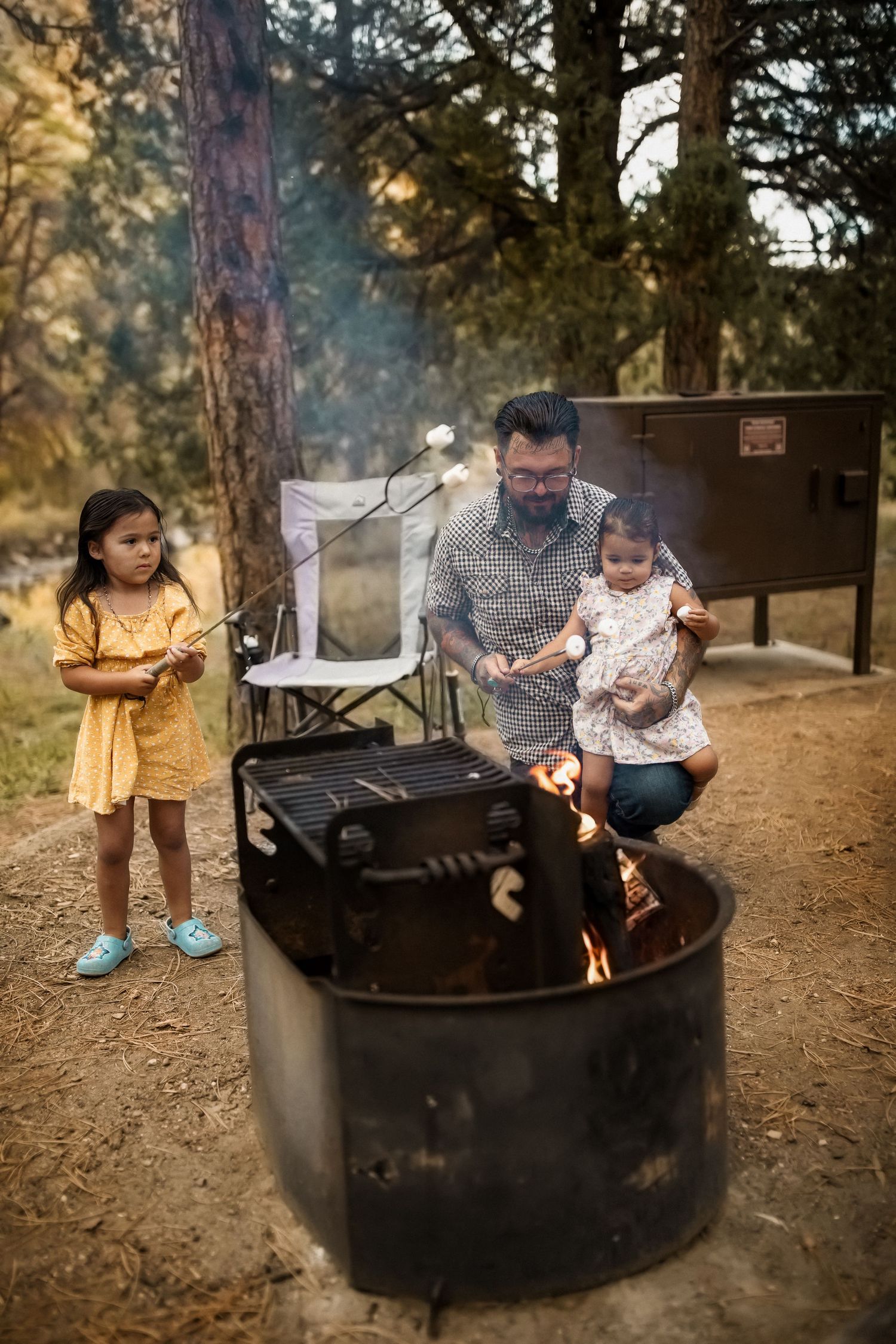 Family gathering around campfire pit in wooded area during outdoor adventure.
