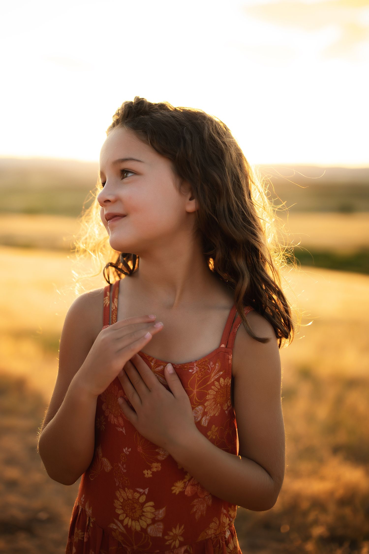 Child expresses joy and wonder during golden hour in a field.