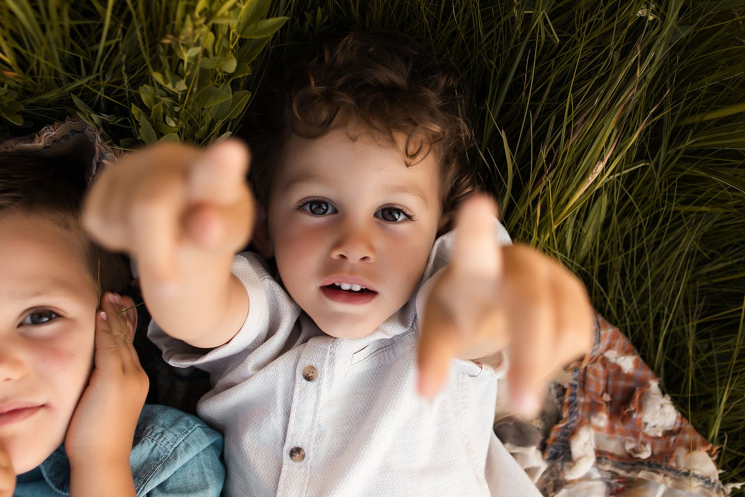 Children playing and gesturing in tall grass during summer.