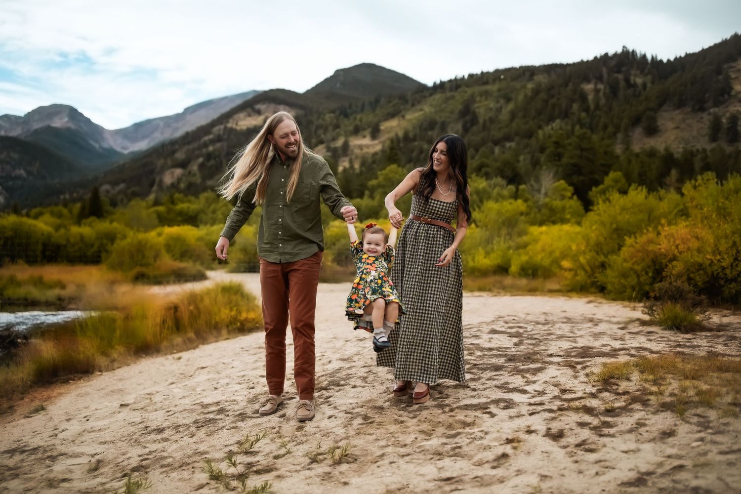 People walking along sandy mountain trail with scenic valley views in background.