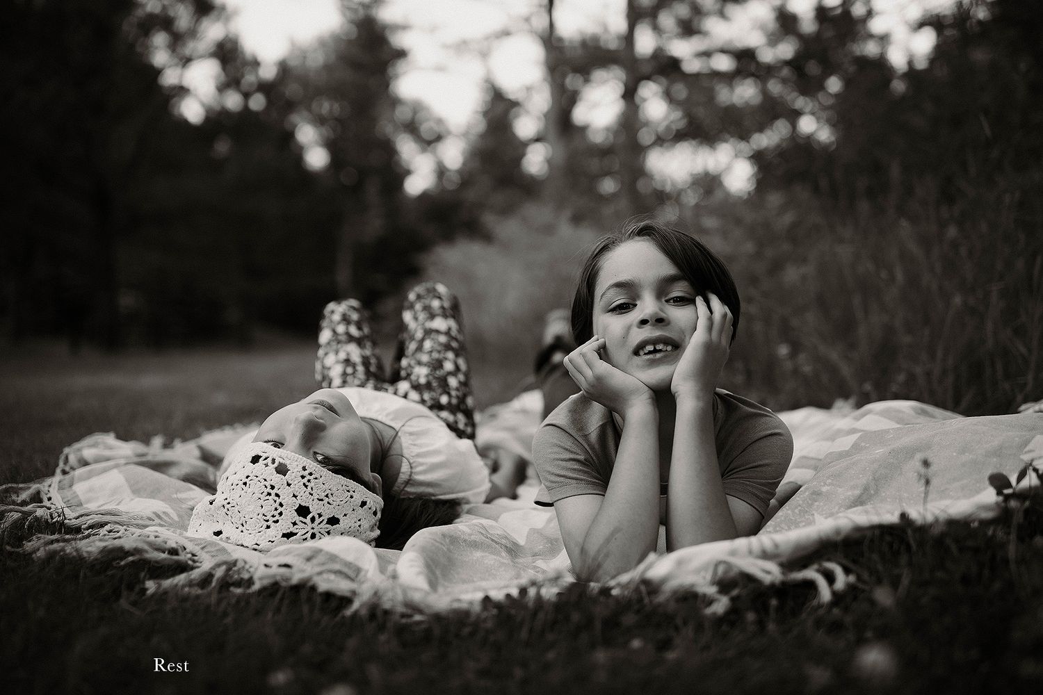Intimate black and white photo of people relaxing on a blanket in a meadow.