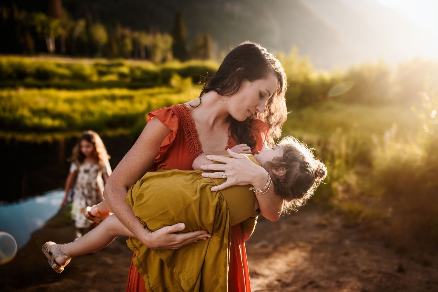 Tender embrace captured in warm sunset light against natural outdoor backdrop.