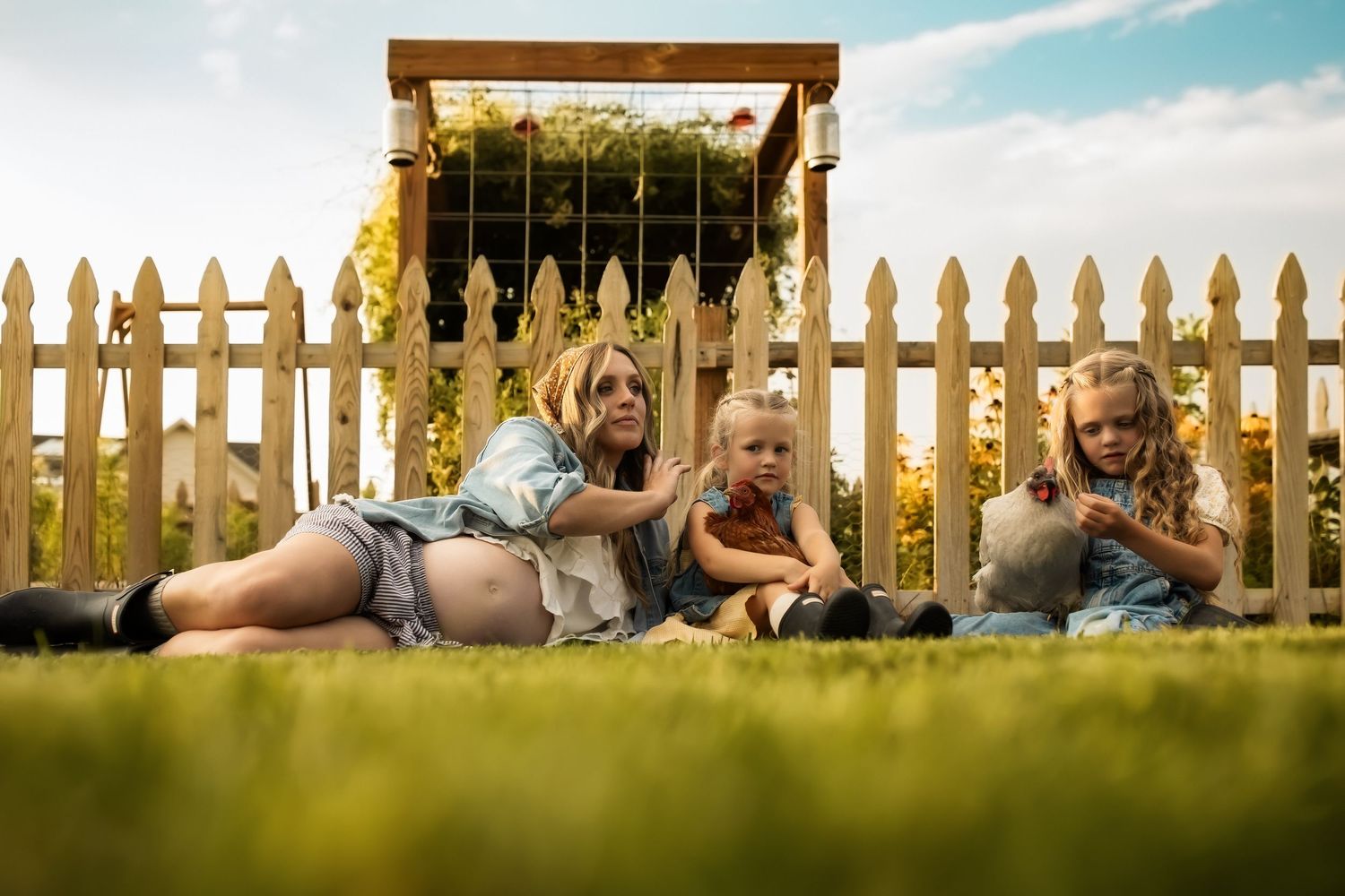 A sequence of five photos showing a couple sitting on grass by a white picket fence at sunset.