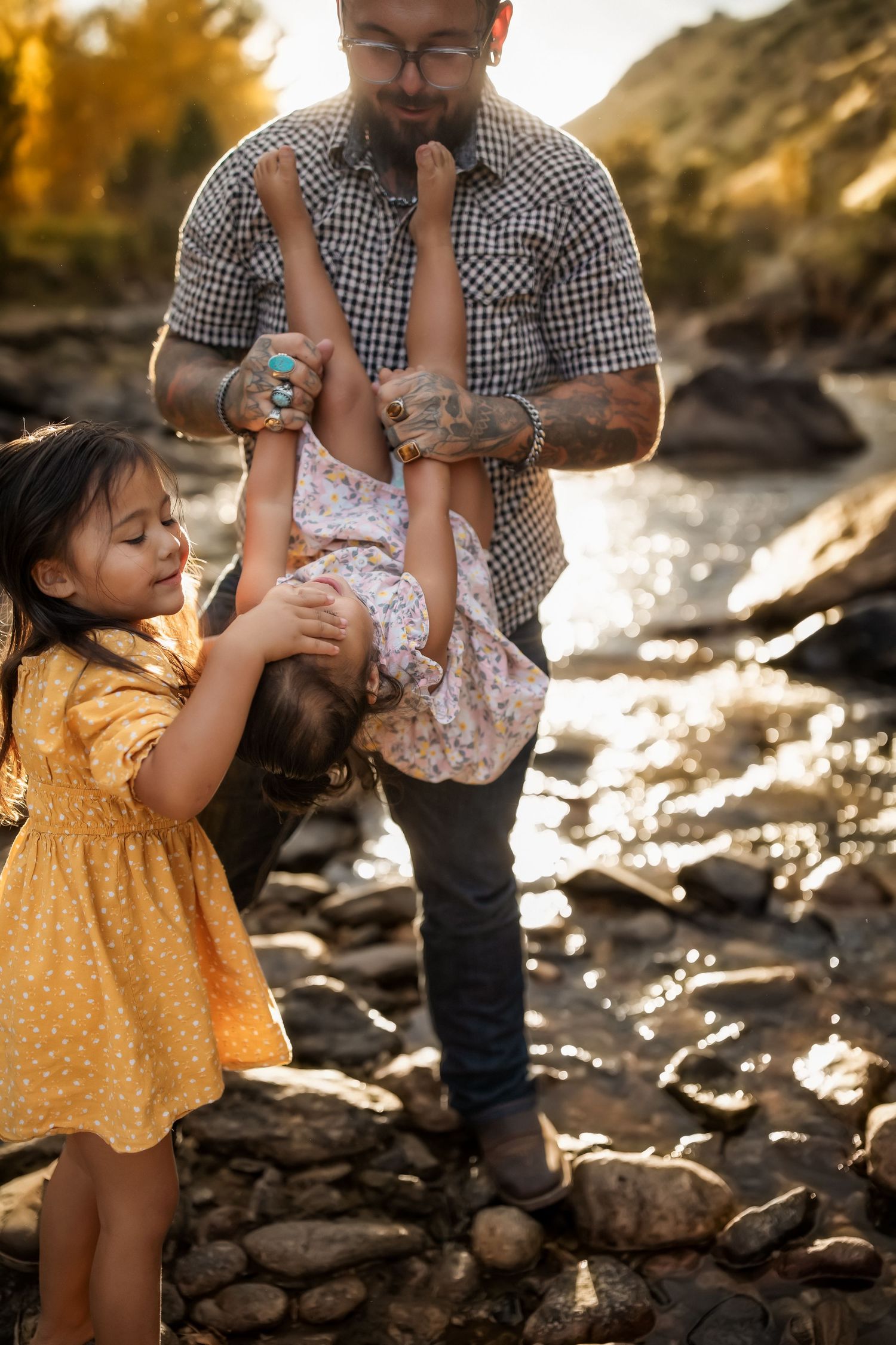 Family enjoying playful moments together on rocky terrain during sunset.