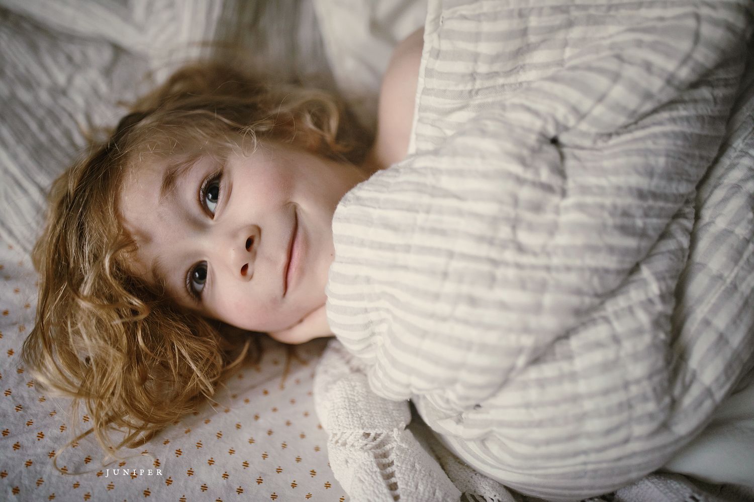Person lying on textured bedding in gentle morning light.