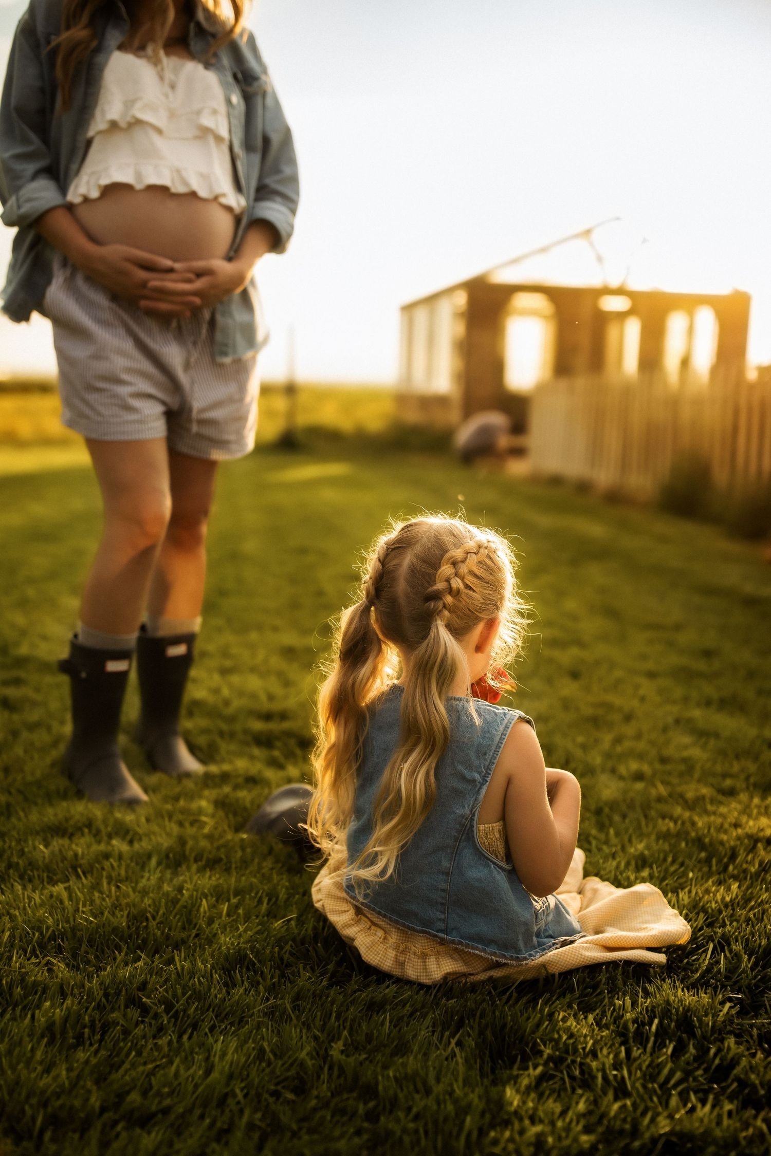 A young reader sits in a grassy field at golden hour with sunlight creating a warm backlit glow.