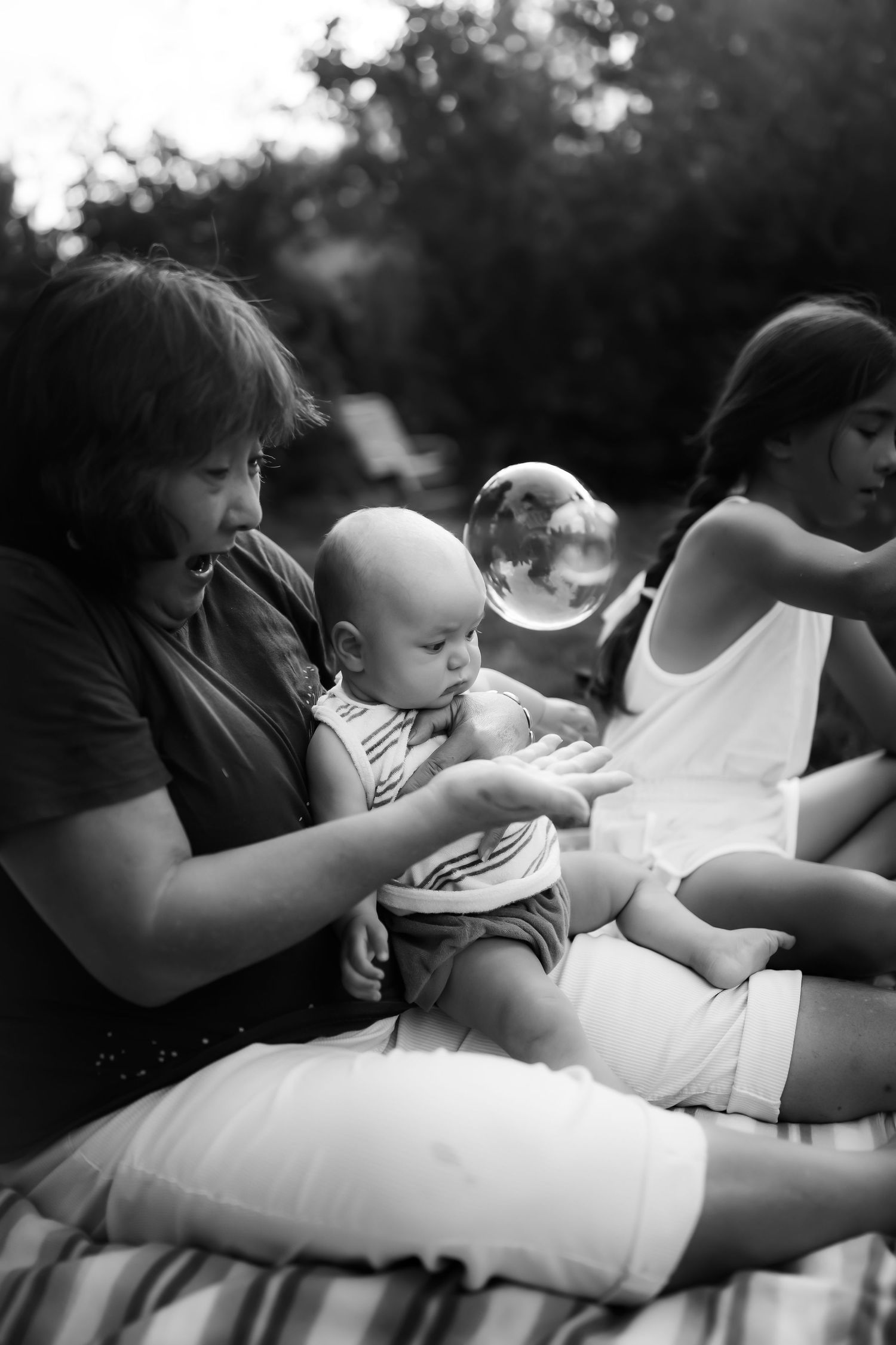A black and white photo series shows tender moments between a parent and baby relaxing together outdoors.
