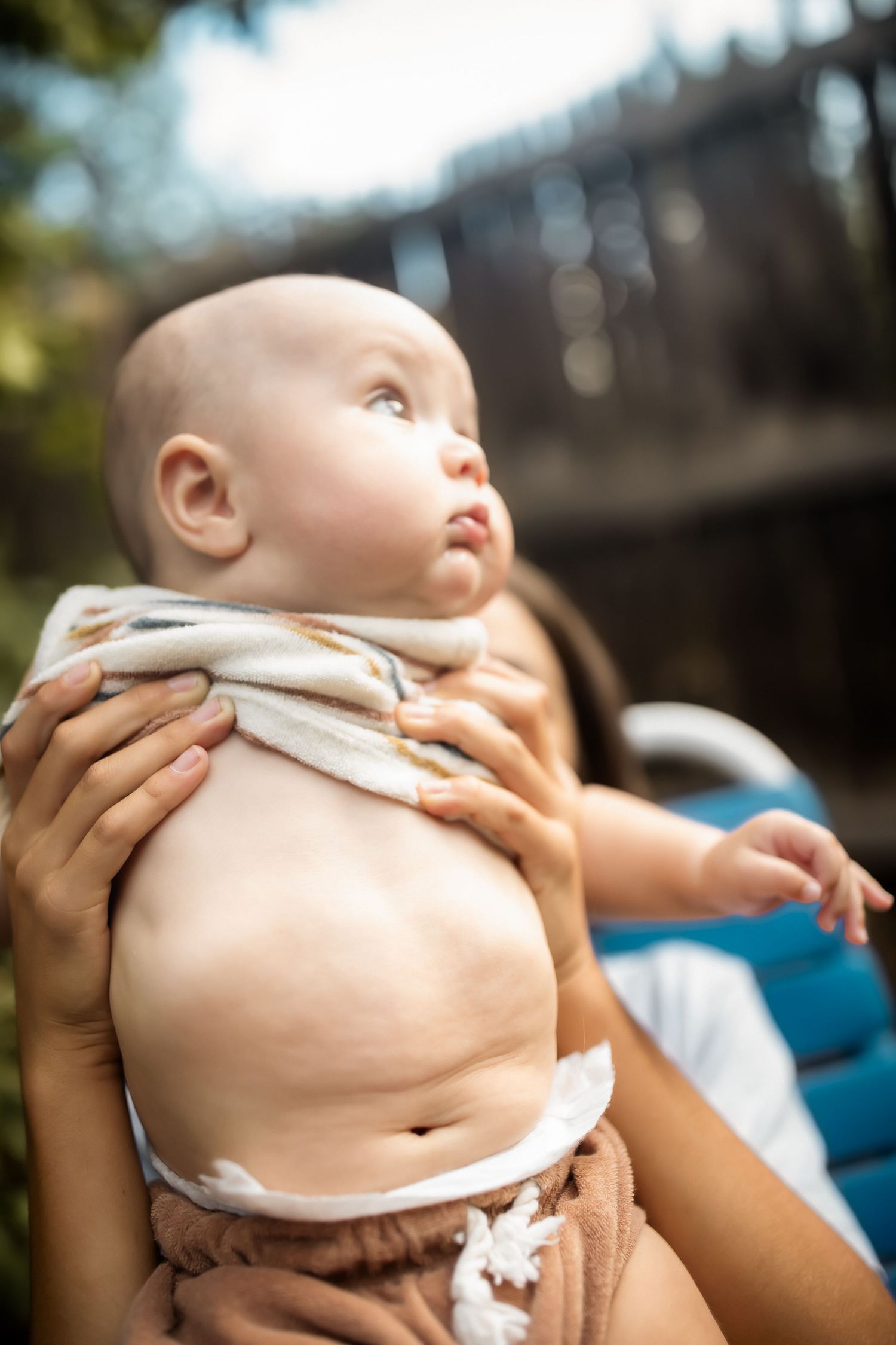 A series of photos showing a baby's bare belly while being held outdoors in natural lighting.