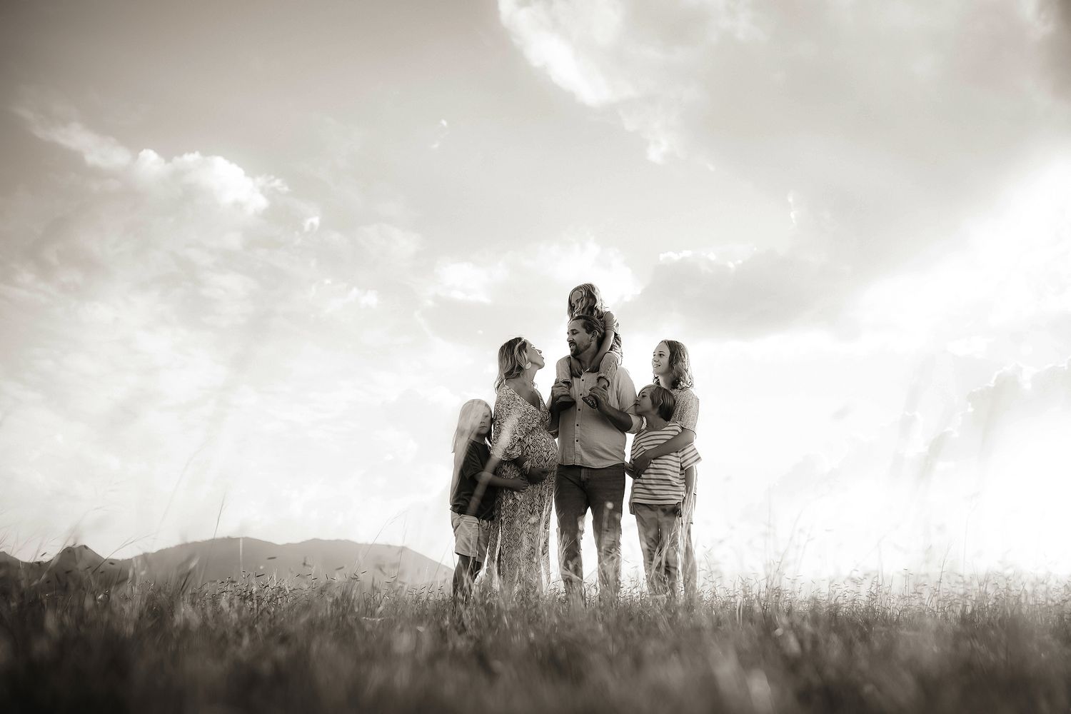 Silhouettes of people standing in a misty field against a cloudy sky.