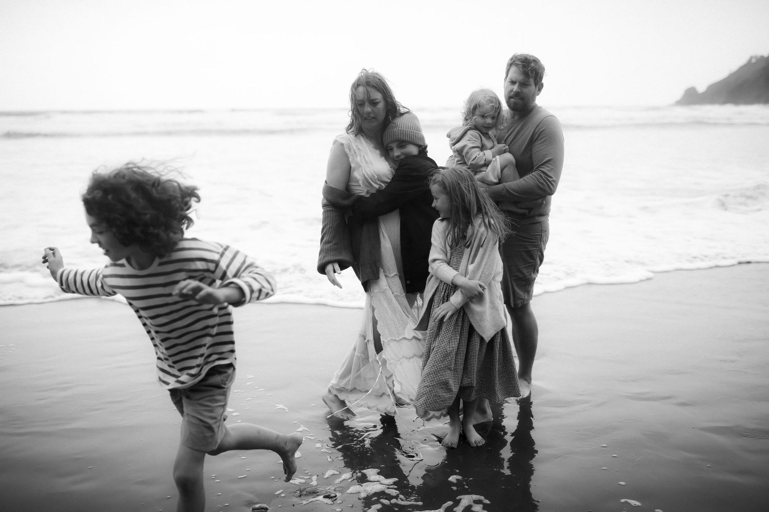 A black and white photo sequence shows a family playing and laughing together on a misty beach.