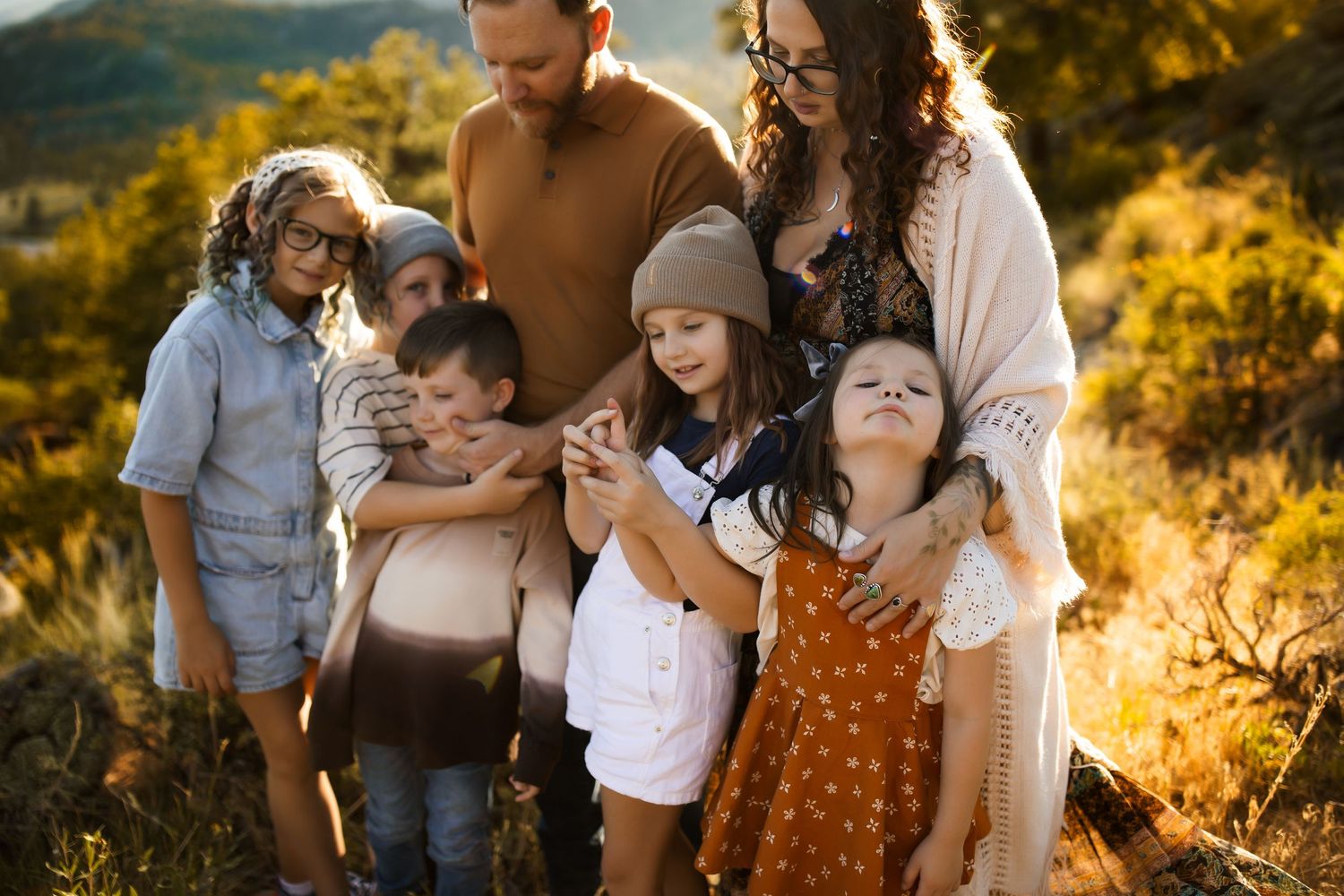 A family photoshoot in golden sunlight with mountains and autumn colors in the background.