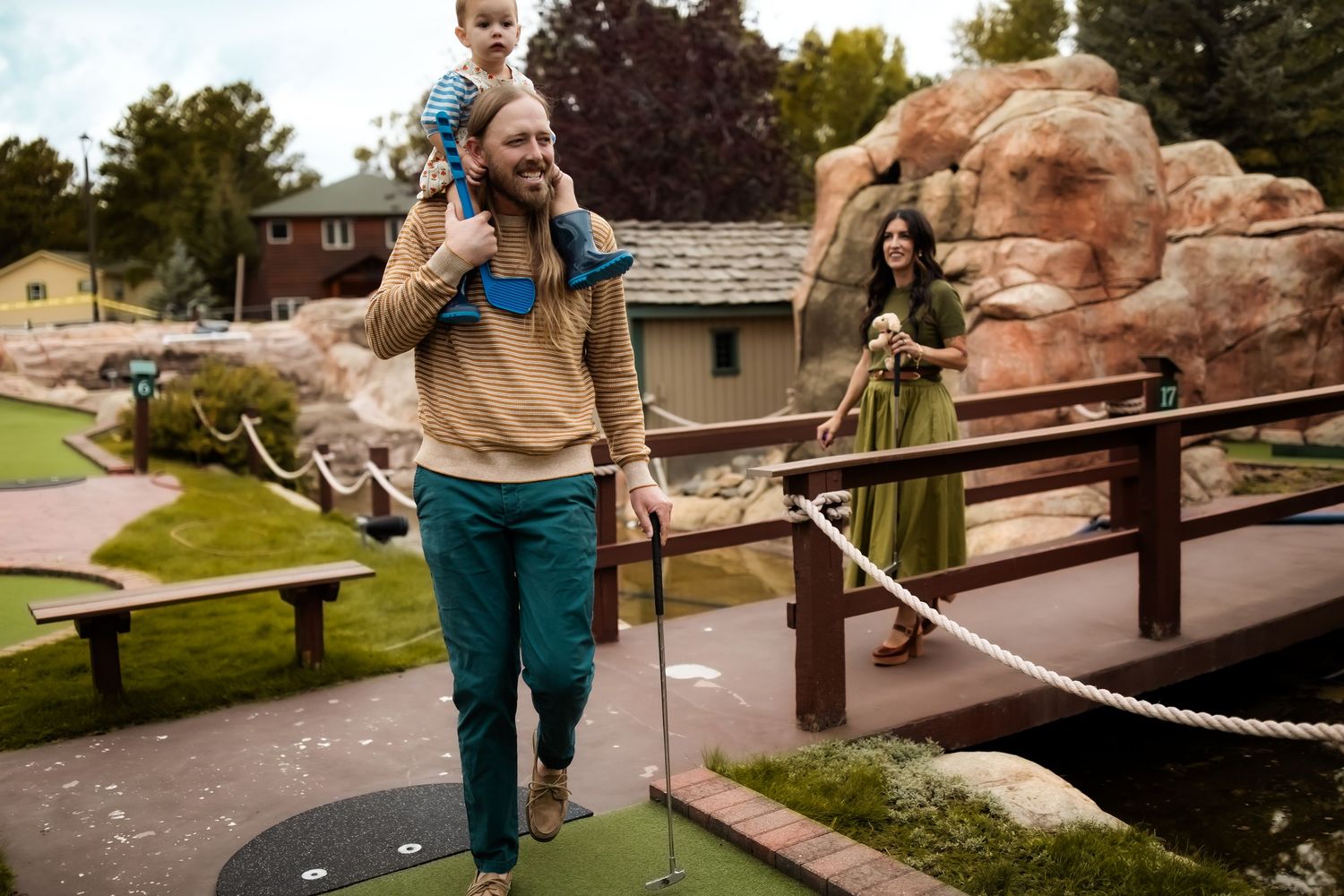 Person walking along outdoor path with rock formations and landscaping.