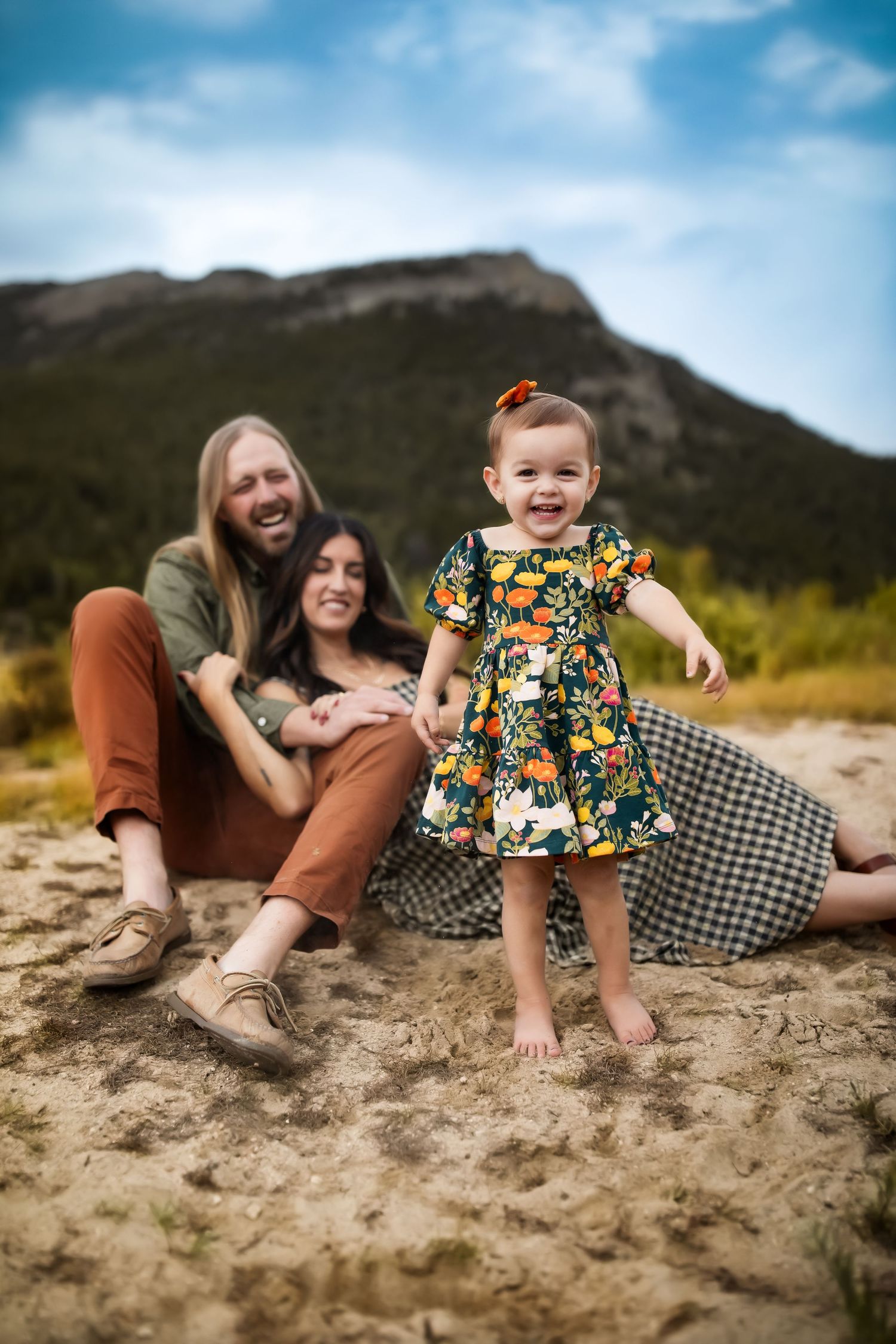Family enjoying a sunny day together on sandy ground with mountains in background.