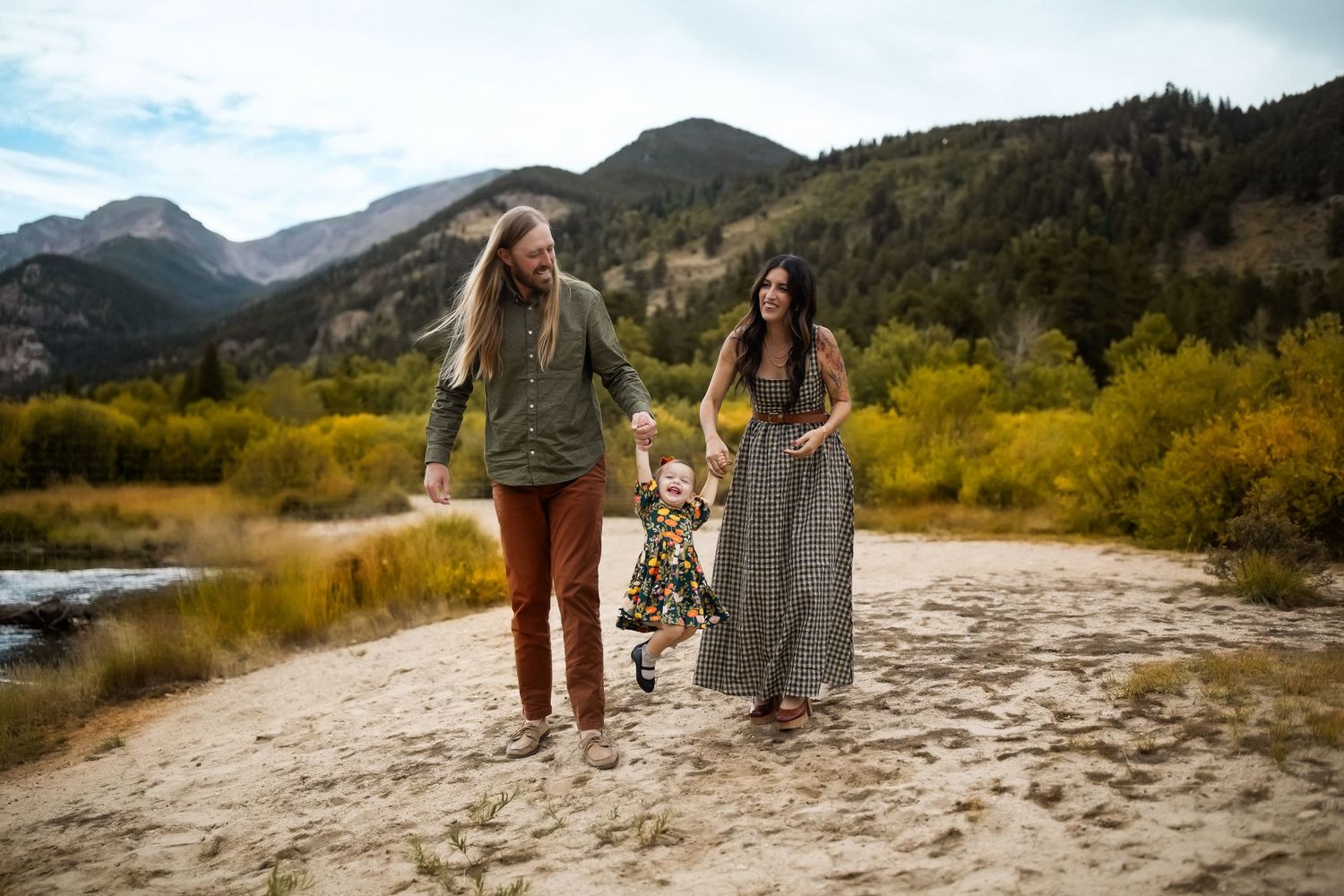 Family walks together on sandy path with mountain landscape in background.