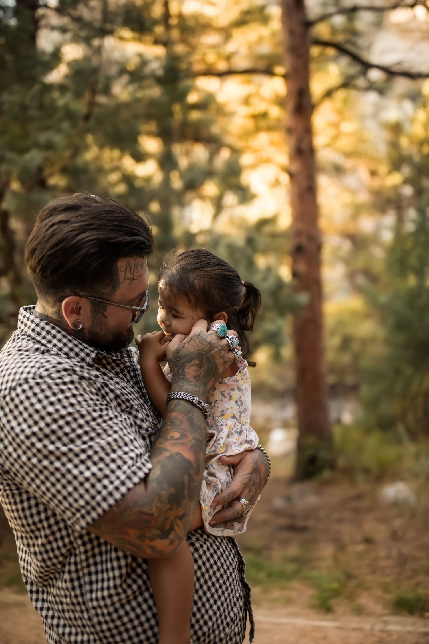 Family sharing tender moment together in pine forest during golden hour.
