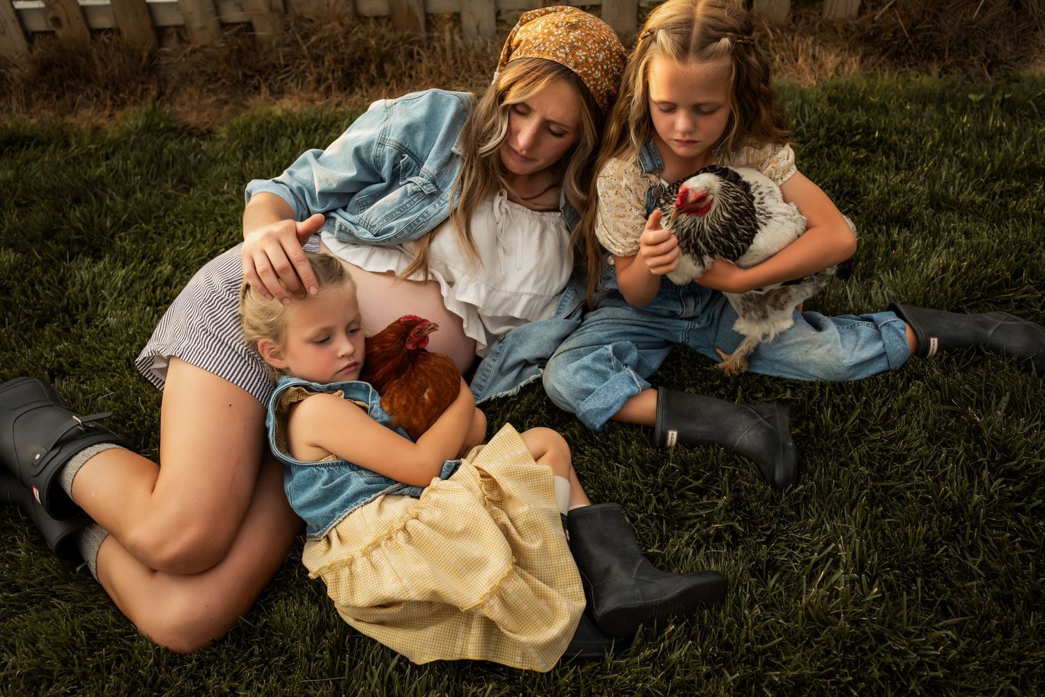 Group cuddling together on grass during outdoor photoshoot.