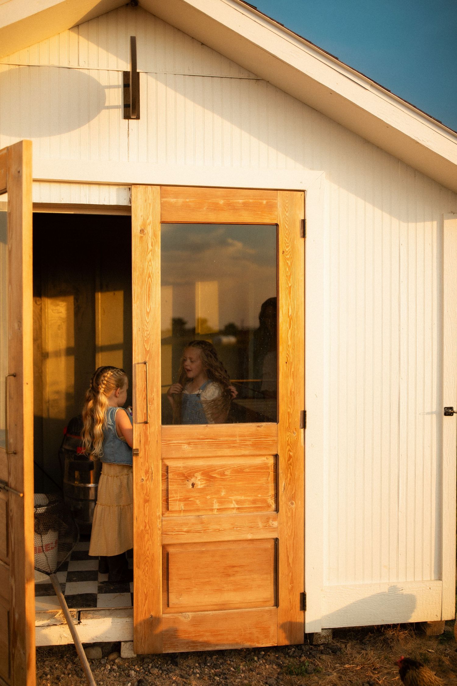 Three small wooden cabins with white exterior walls and wooden doors stand in a row against a blue sky at sunset.
