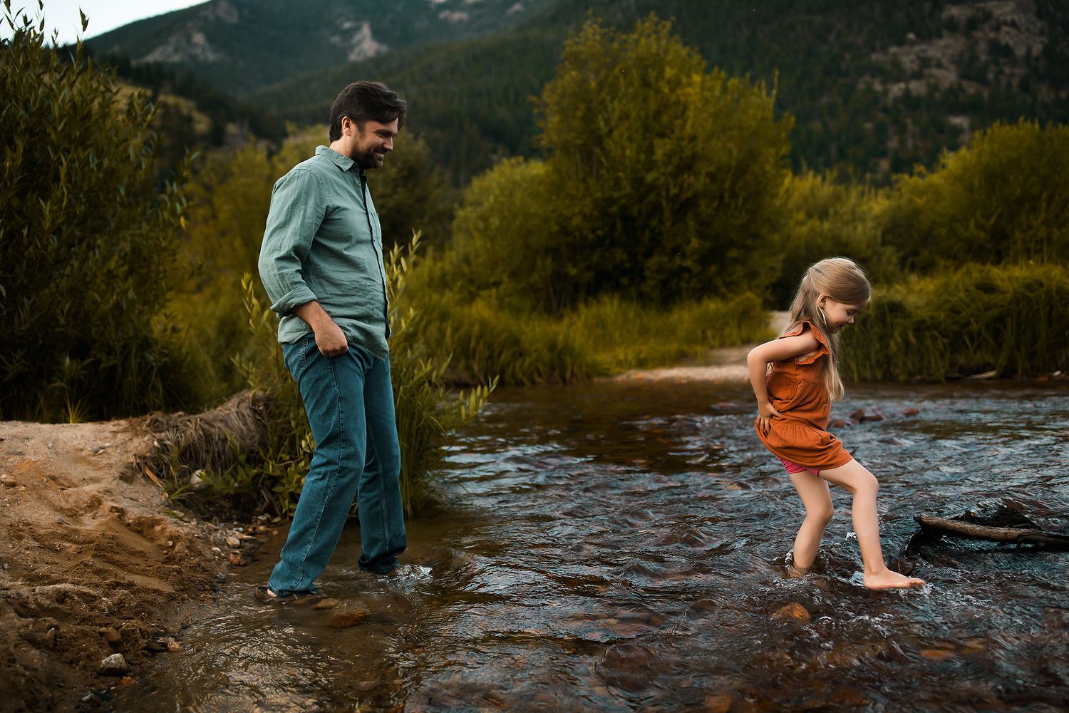 Family playing and splashing together in a mountain stream during a summer adventure.
