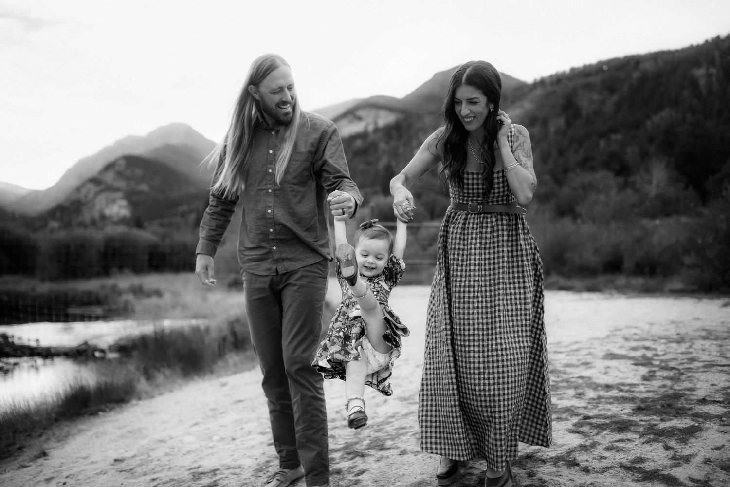 Family walking together along mountain stream in black and white photograph.