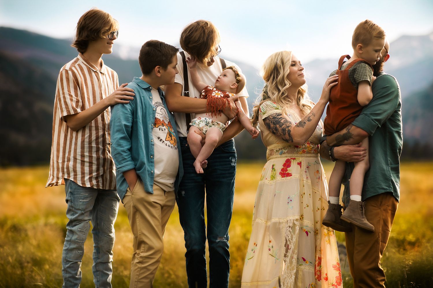 Group of people embracing outdoors in casual attire against natural backdrop.