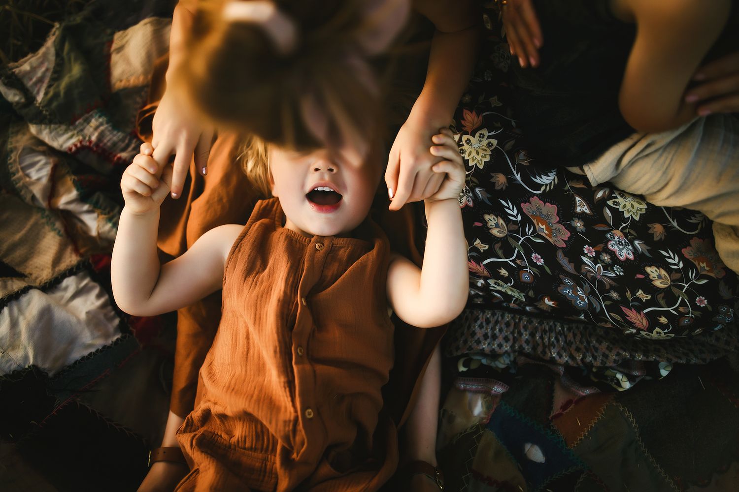 A child in an orange outfit playing and making silly expressions.