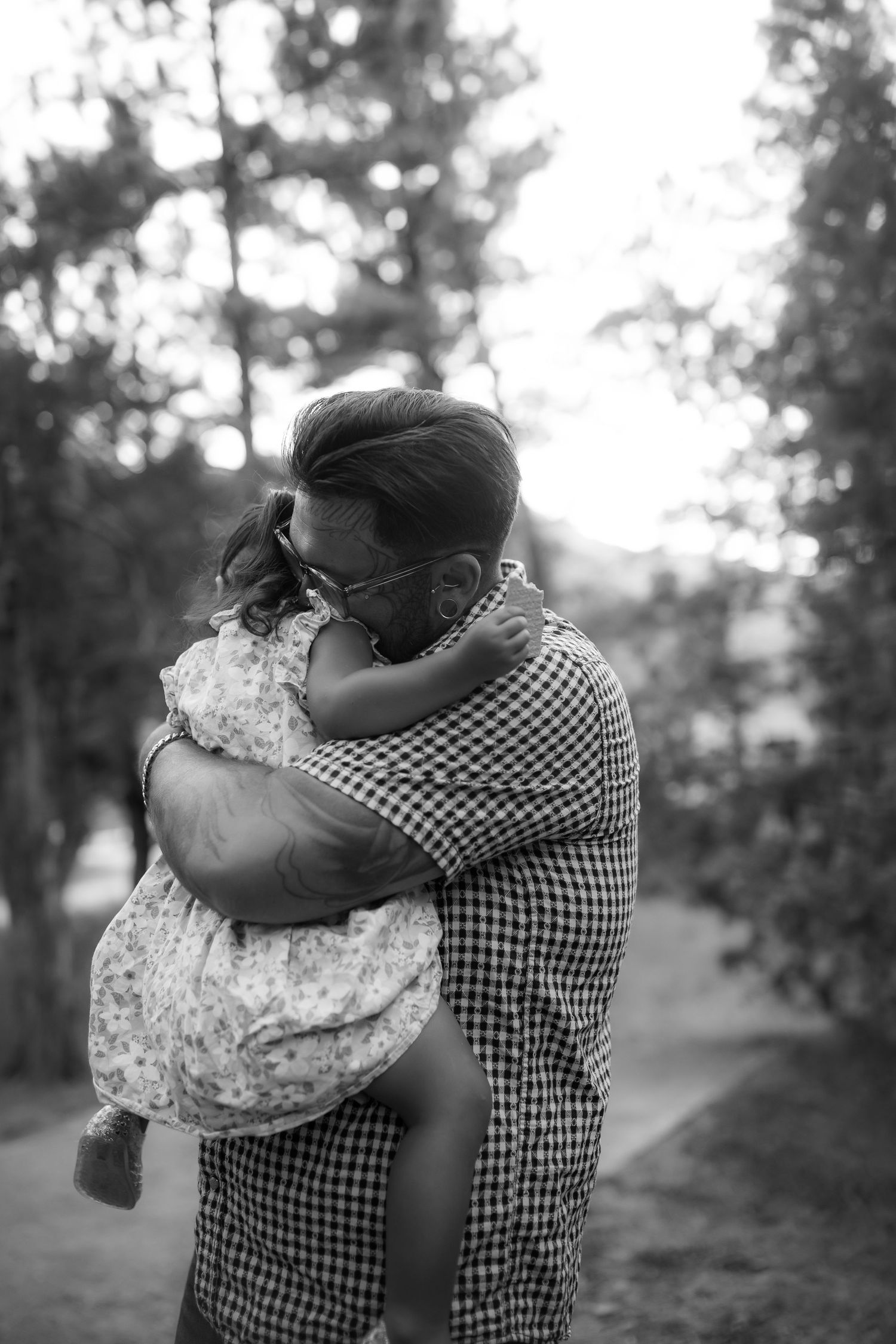 Black and white images showing tender embraces outdoors with gingham shirt and floral dress patterns.
