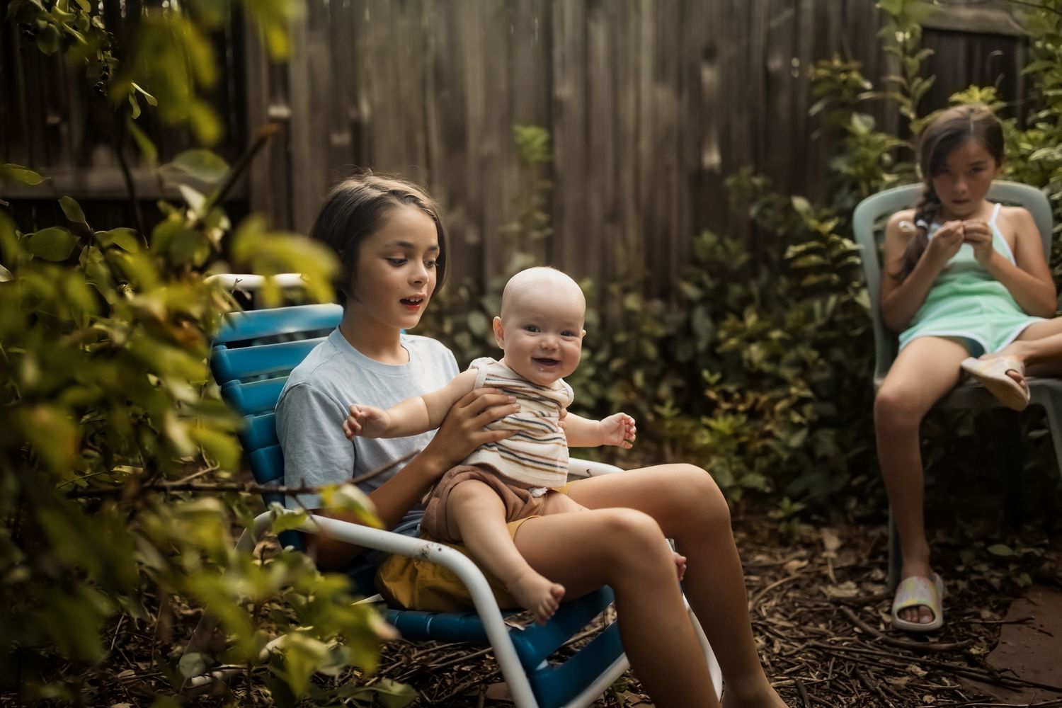People relaxing in lawn chairs on a summer evening in a backyard garden setting.