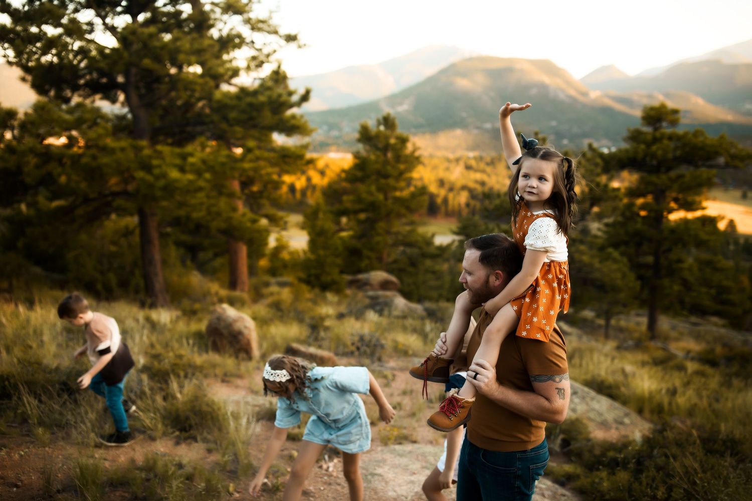 A group enjoys a scenic mountain hike at sunset with pine trees and golden light illuminating the landscape.