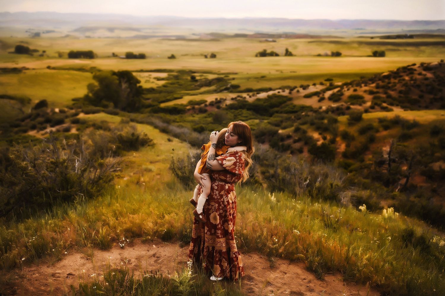 Person in floral dress walking along scenic hilltop trail during golden hour.