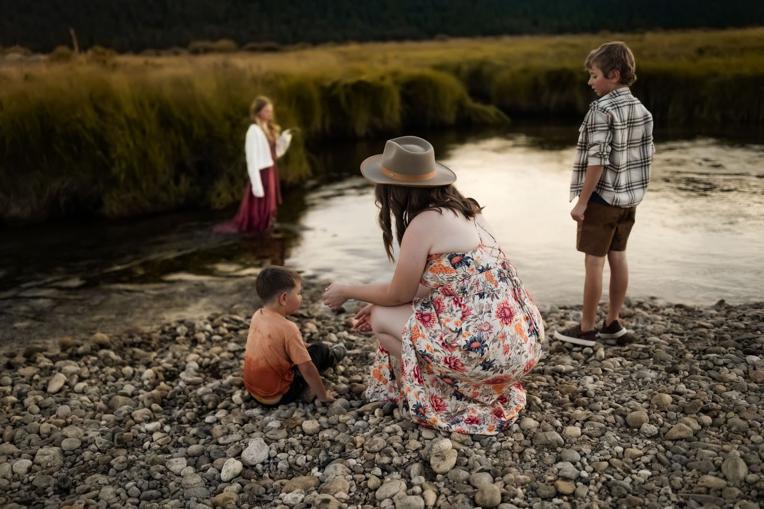 Family bonding together by a rocky riverbank on a peaceful afternoon.
