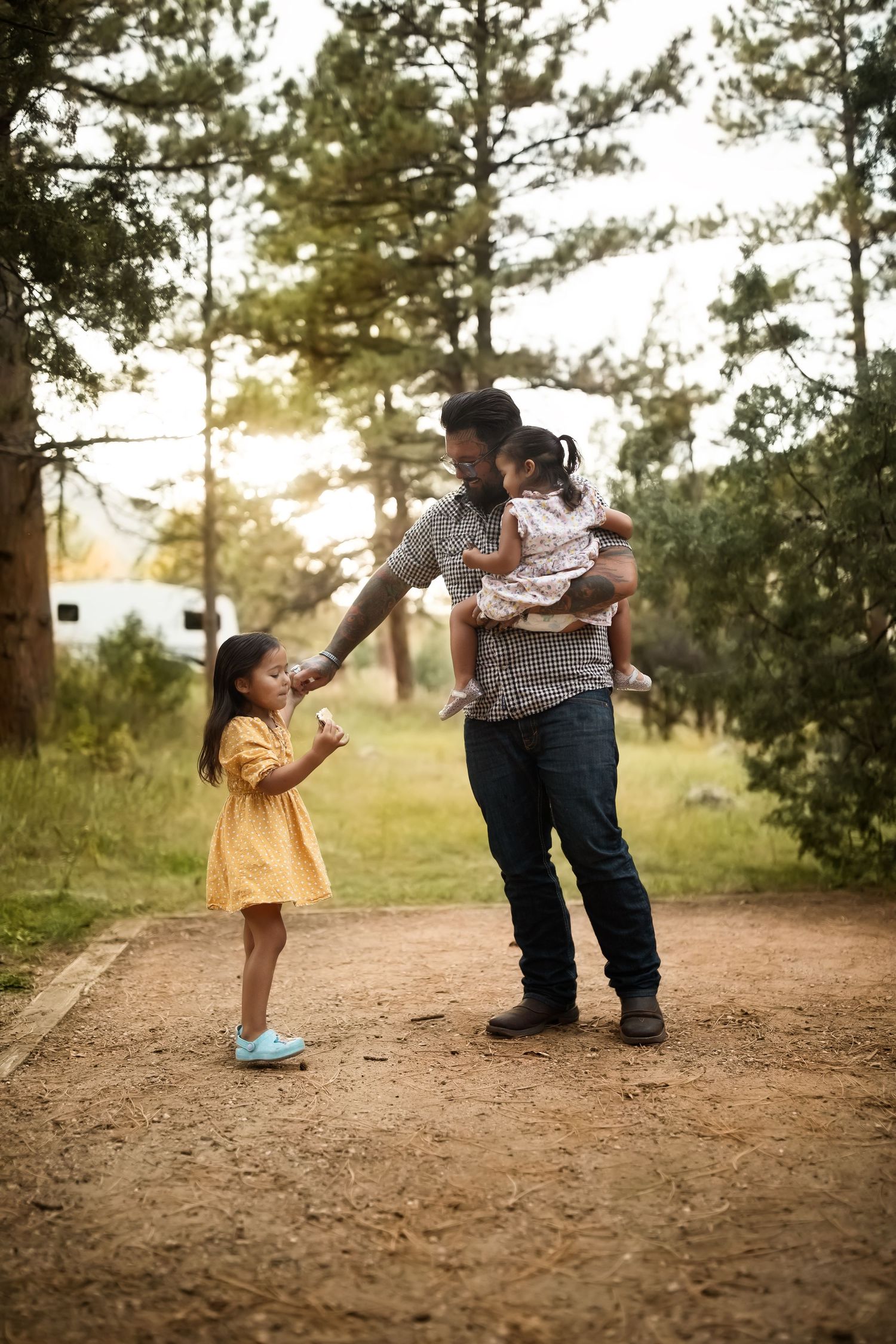 Parent and child sharing playful moments on a dirt path surrounded by pine trees.
