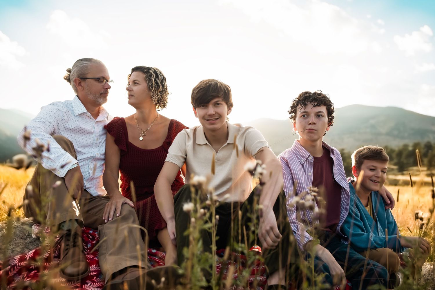 A group of people gather outdoors at sunset in a field, creating a warm and joyful atmosphere.