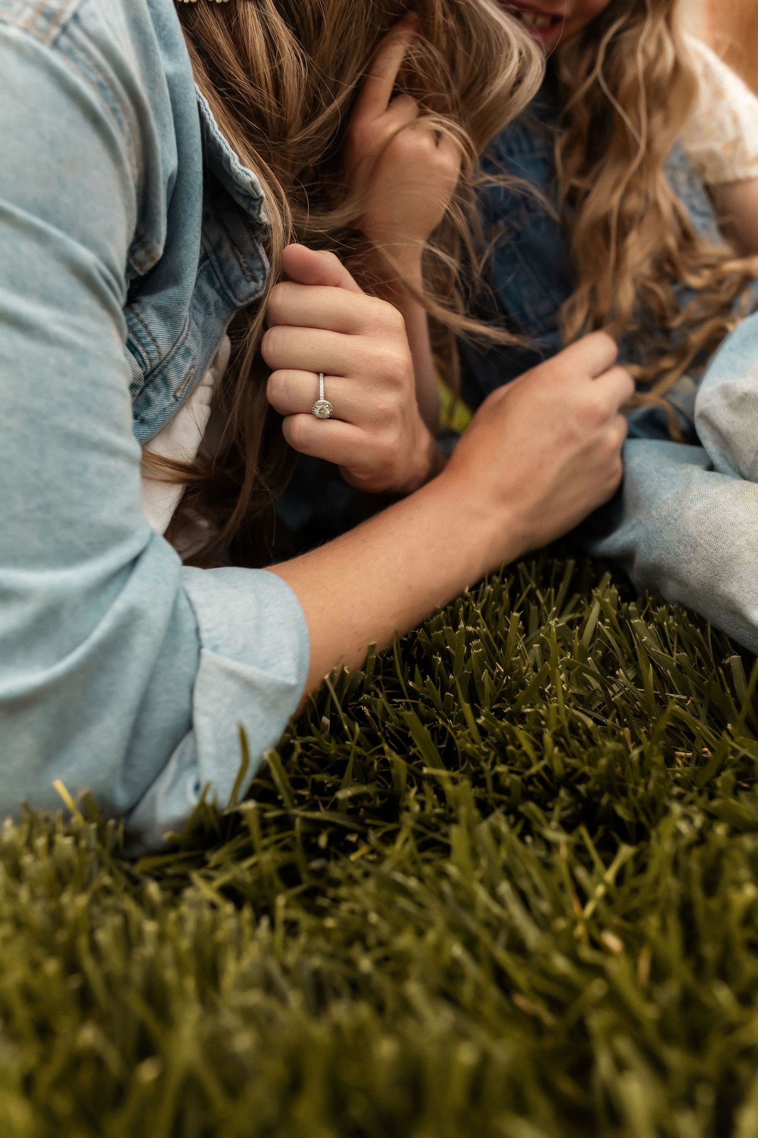 Person lying on green grass wearing denim jacket in warm sunlight.
